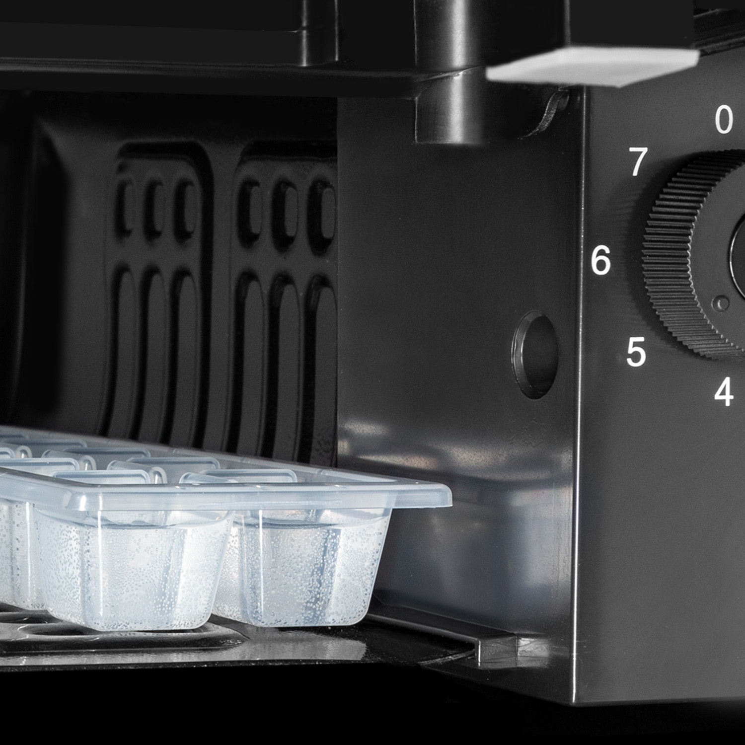 Primer plano de una máquina de hacer hielo con una bandeja de cubitos de hielo en un compartimento.