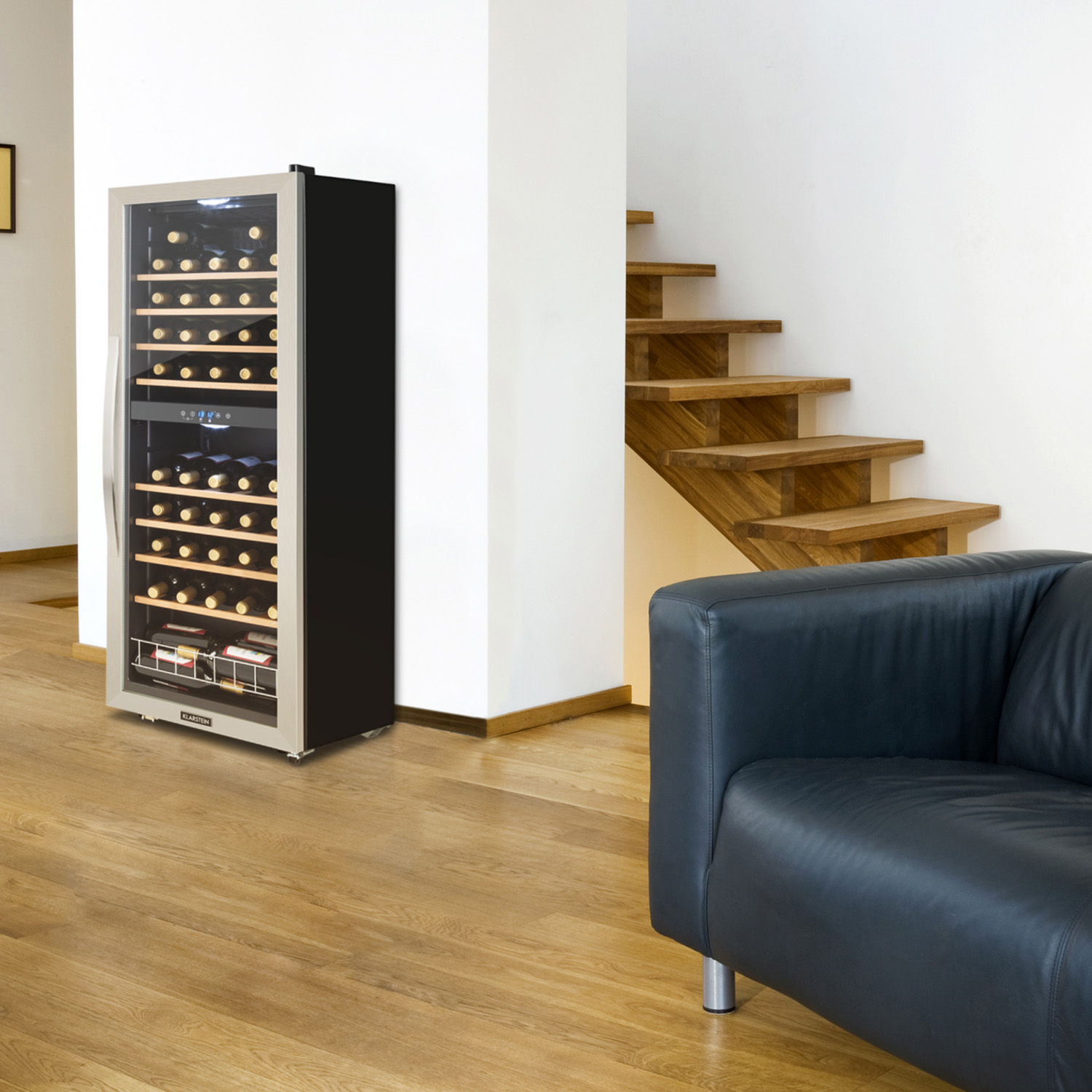 Weinkühler mit Flaschen, Holzboden, Treppe und schwarzem Ledersofa rechts.