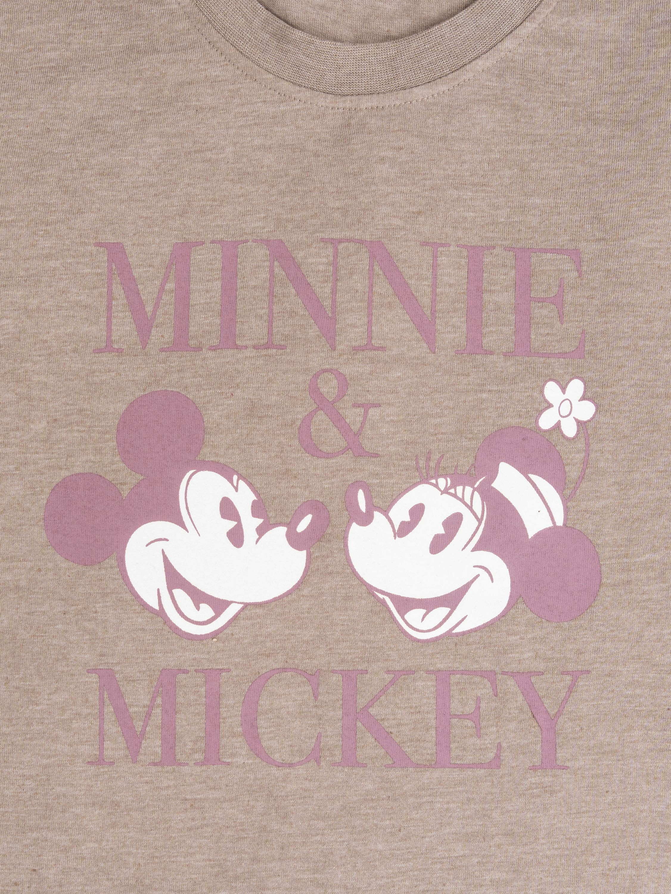 Nahaufnahme eines beigefarbenen T-Shirts mit Minnie- und Mickey-Mouse-Gesichtern und Text.