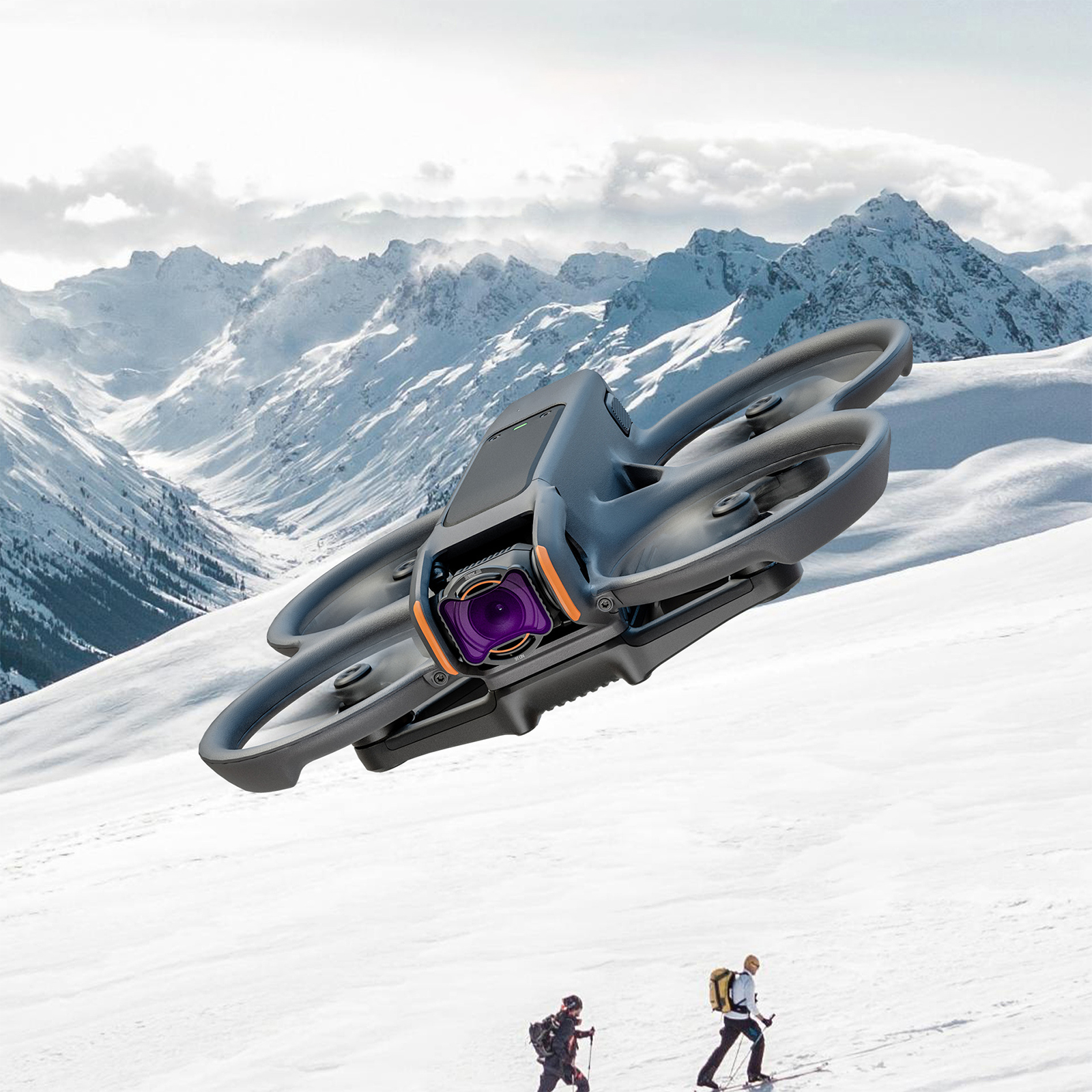 Drohne fliegt über schneebedeckten Bergen. Zwei Skifahrer im Vordergrund.