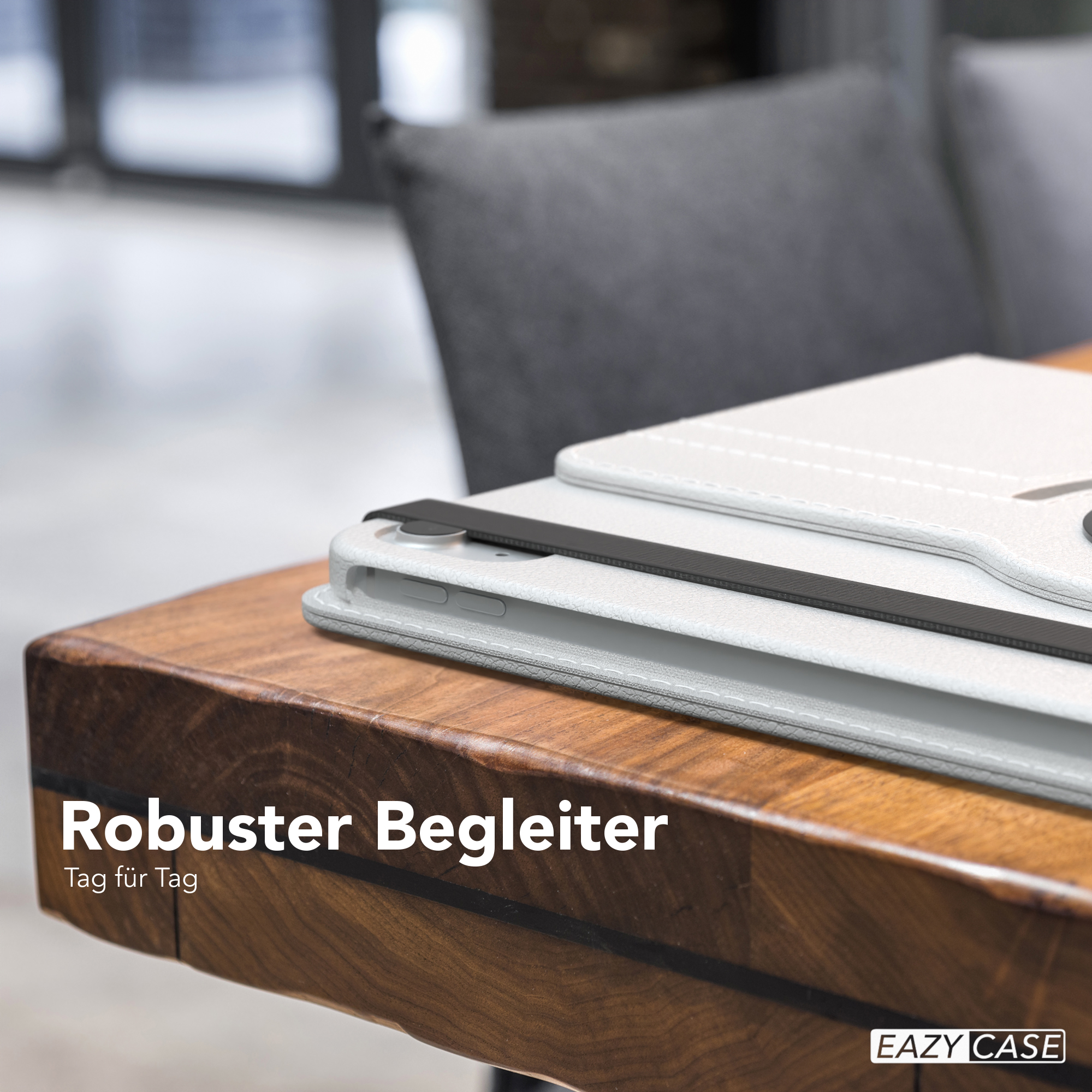 Weiße Tablethülle auf Holztisch. Text: 'Robuster Begleiter'. Dunkler Stuhl im Hintergrund.