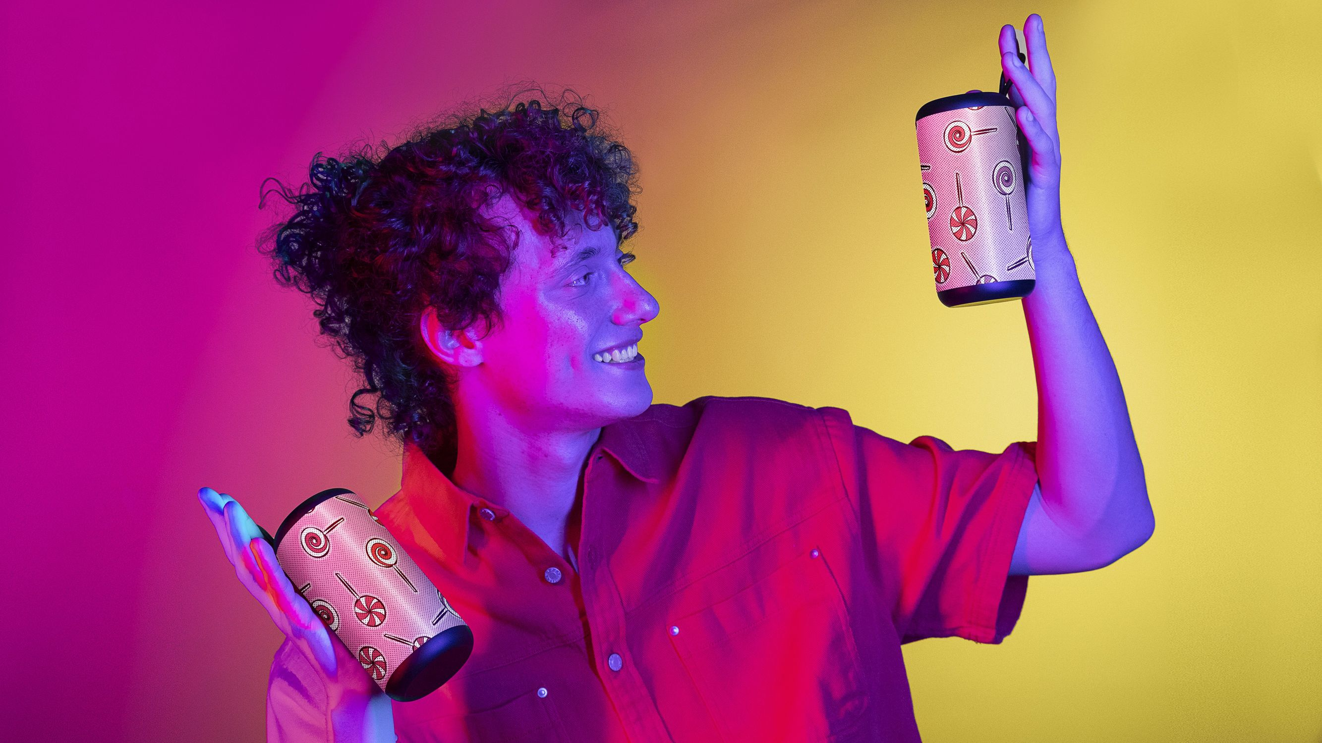 Mężczyzna trzymający dwa głośniki z wzorami cukierków, uśmiechając się.