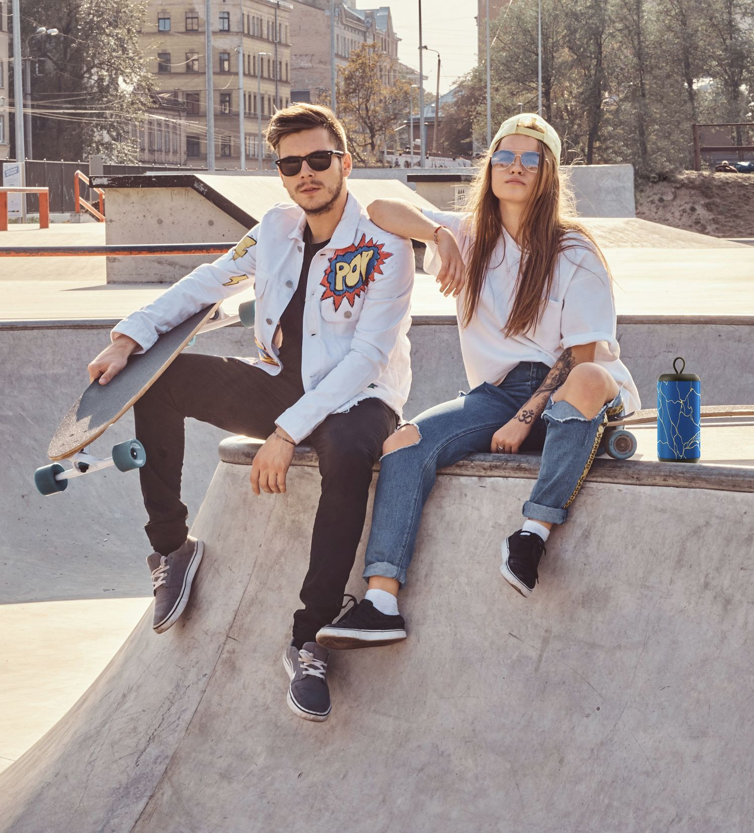 Para siedzi w skateparku. Mężczyzna trzyma deskorolkę, kobieta siedzi obok niego.