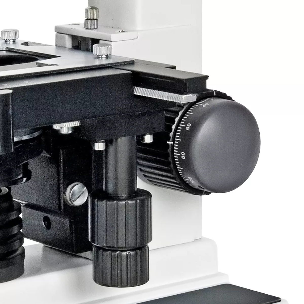 Primer plano de un microscopio con perillas negras y fondo blanco.