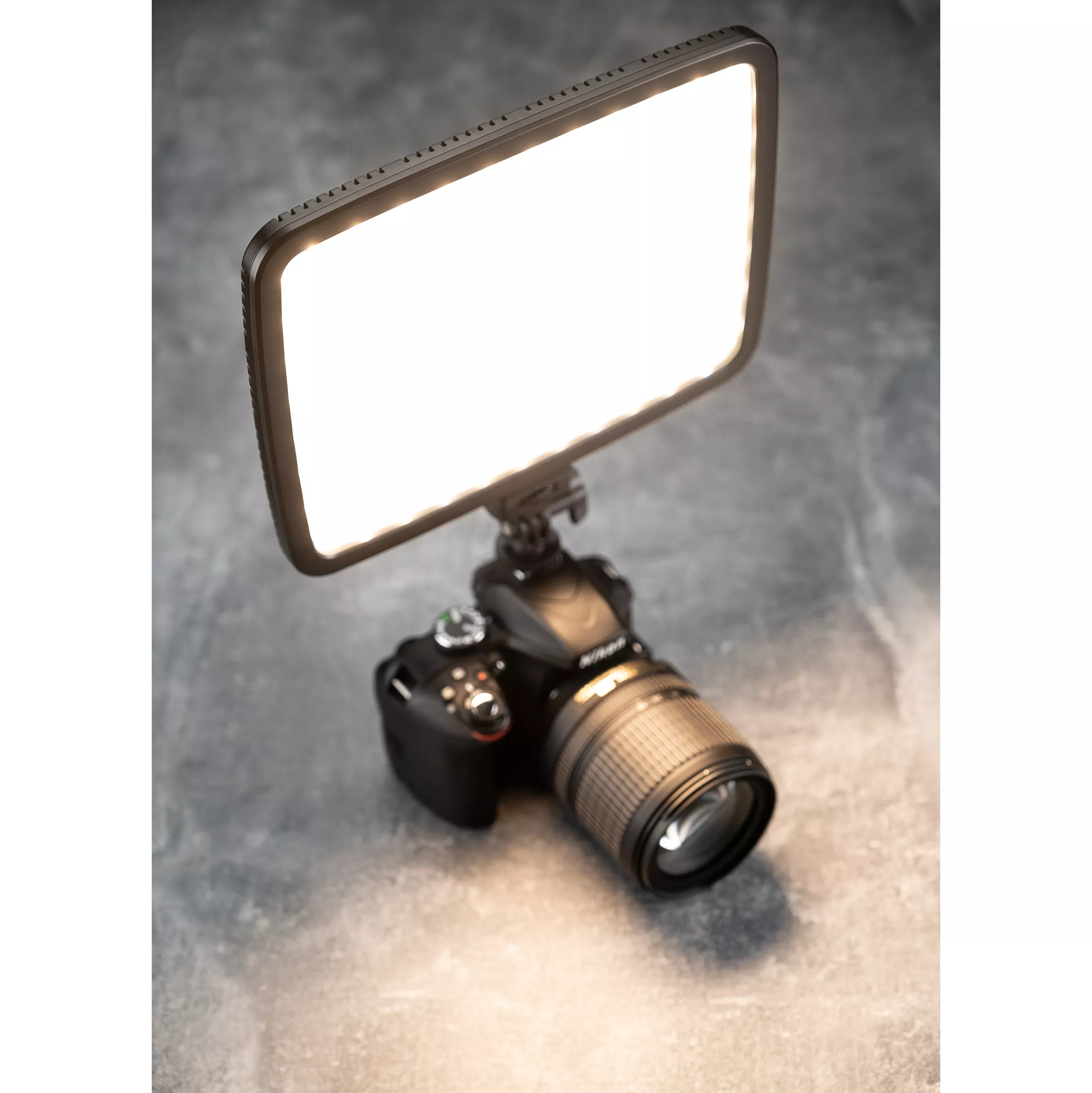 A camera with a bright LED light attached. Light is rectangular and facing upwards.