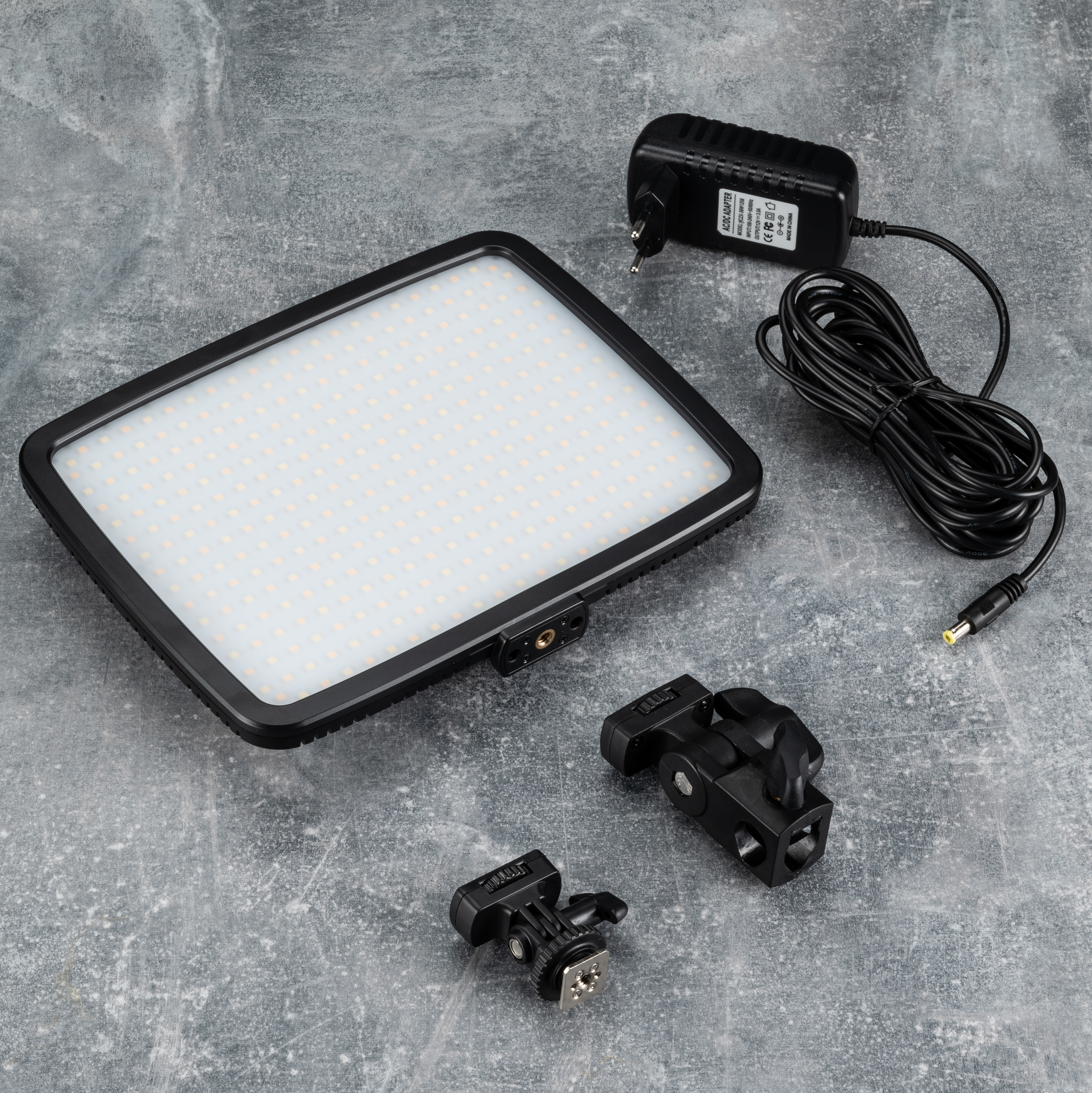 A black LED light panel with accessories, with a gray background.