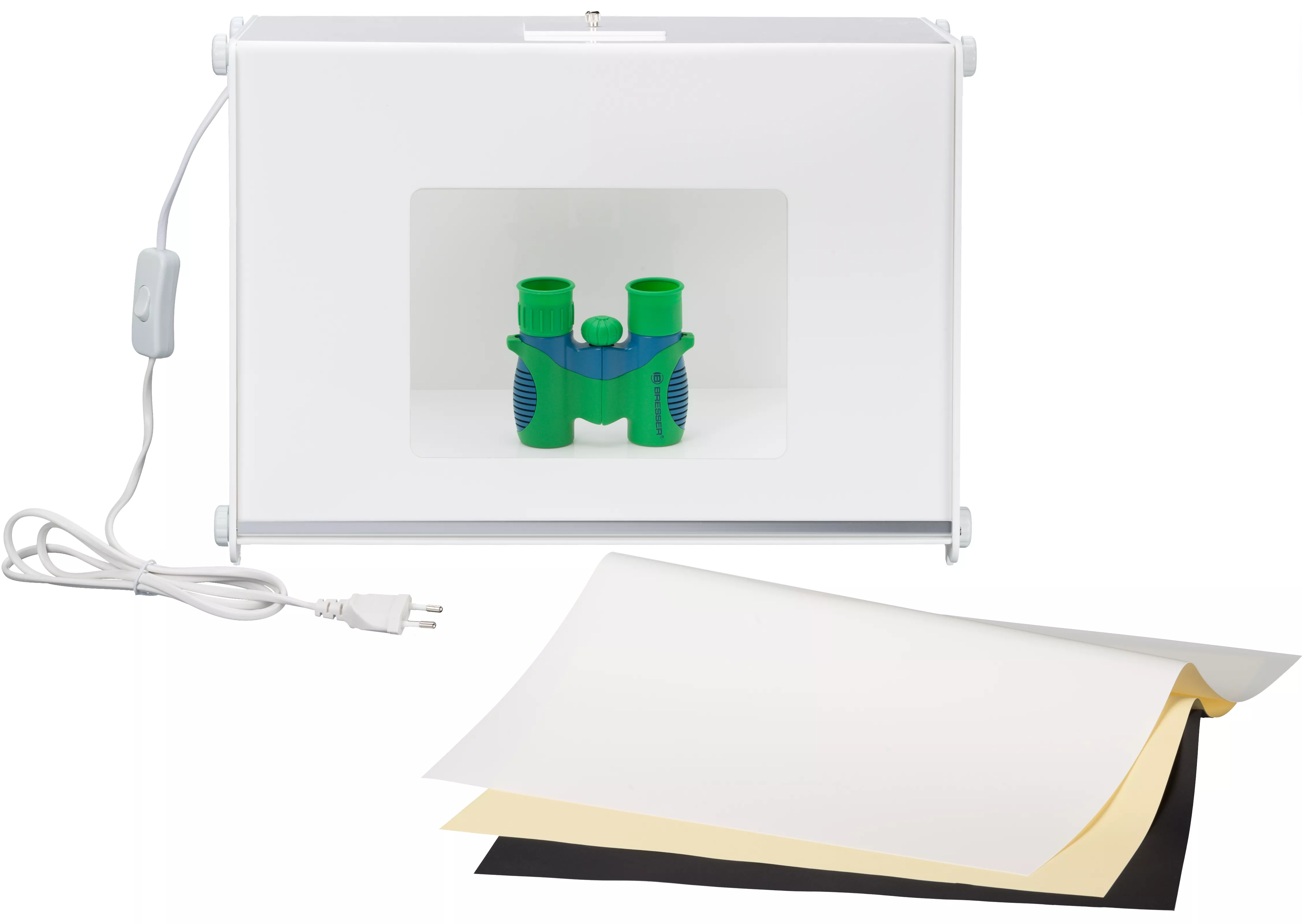 Caja de estudio fotográfico blanca con prismáticos verdes y azules y papeles de colores.