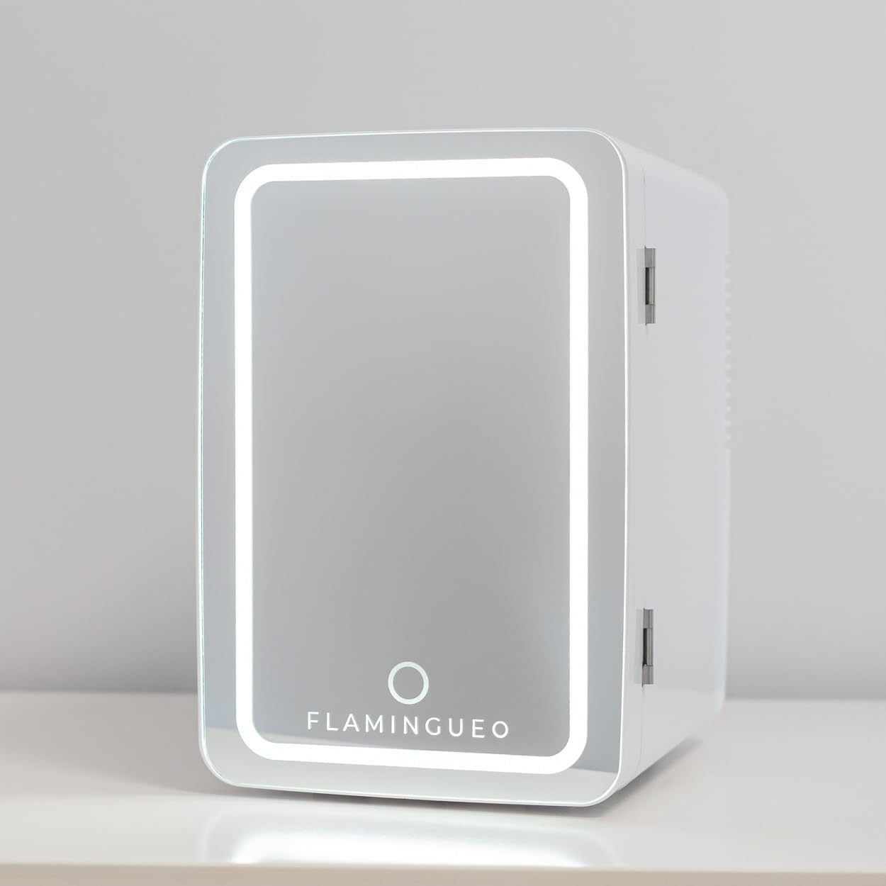 Un mini-refrigerador blanco con puerta espejada y marco luminoso. La marca está en la parte inferior.