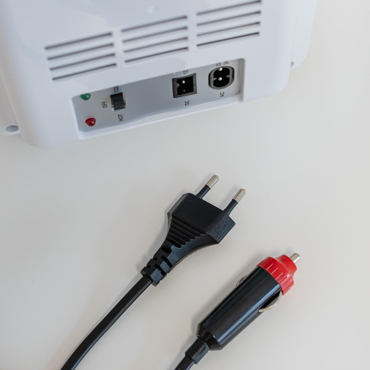 Dispositivo blanco con enchufe y cable de cargador de coche. Fondo blanco.