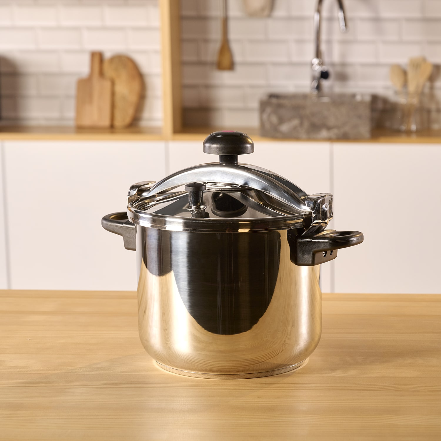 Olla a presión de acero inoxidable brillante sobre una encimera de madera en una cocina.