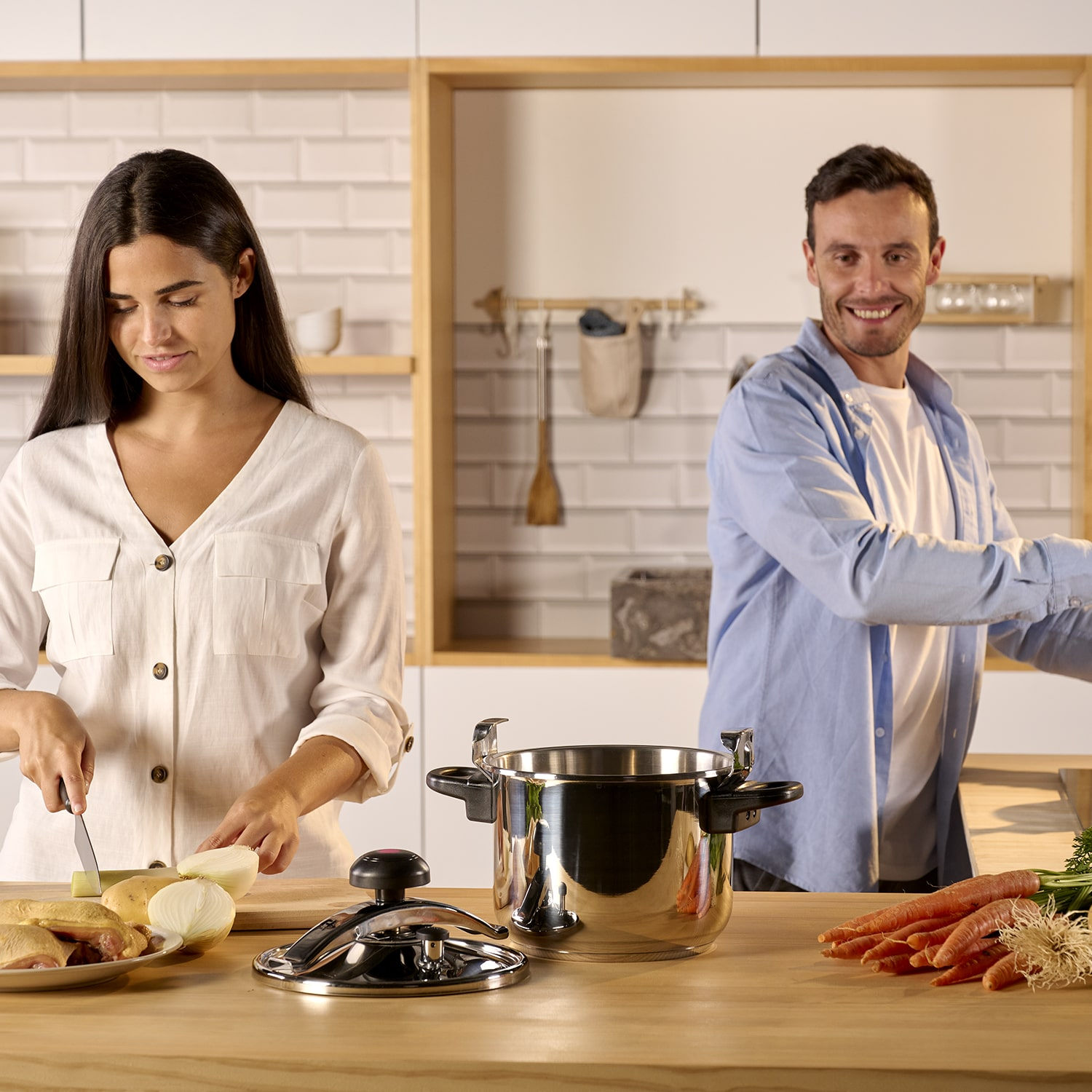 Dos personas cocinando en una cocina, con una olla y verduras en el mostrador.