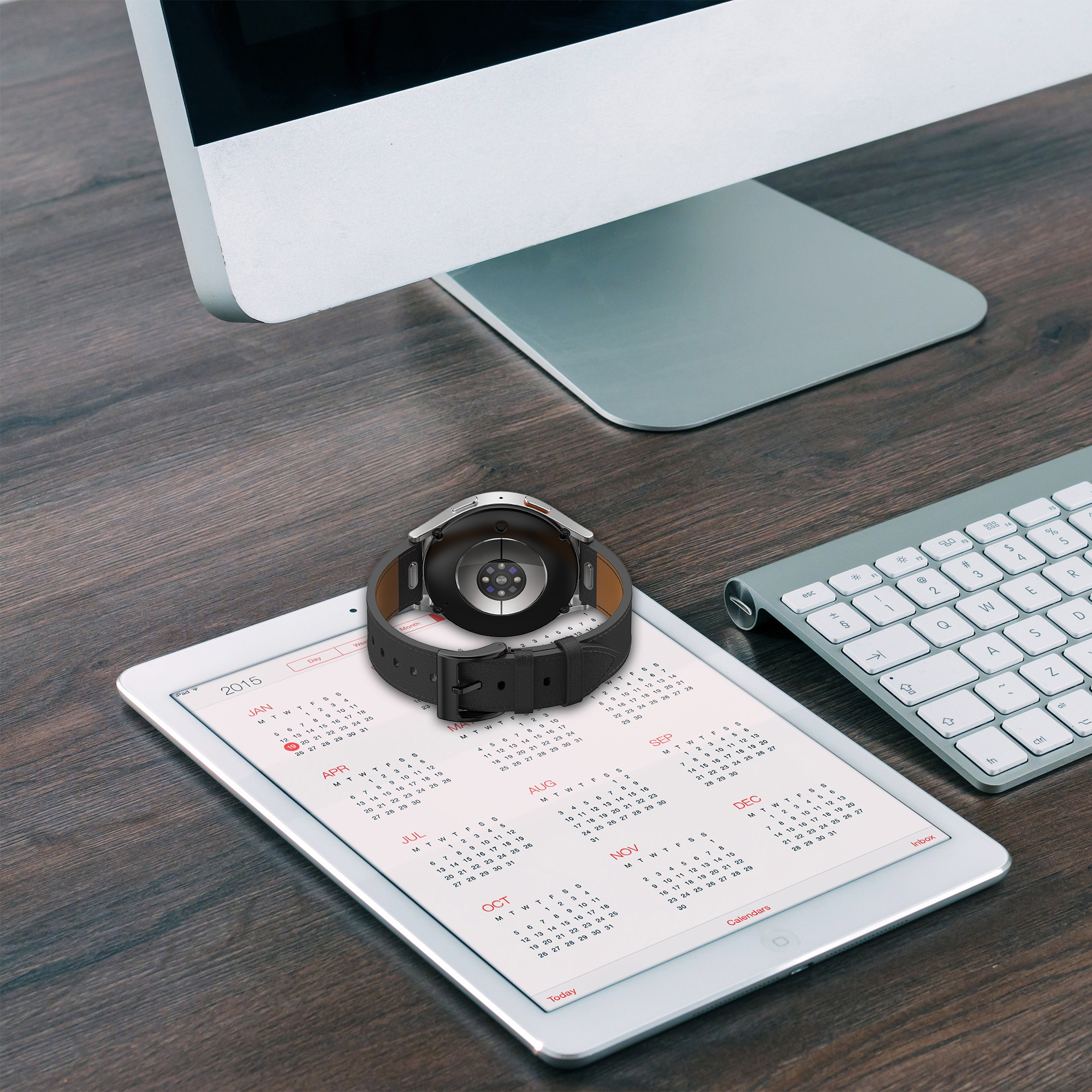 Smartwatch auf einem Kalender. Die Uhr ist schwarz mit schwarzem Armband. Der Kalender ist auf einem Tablet.