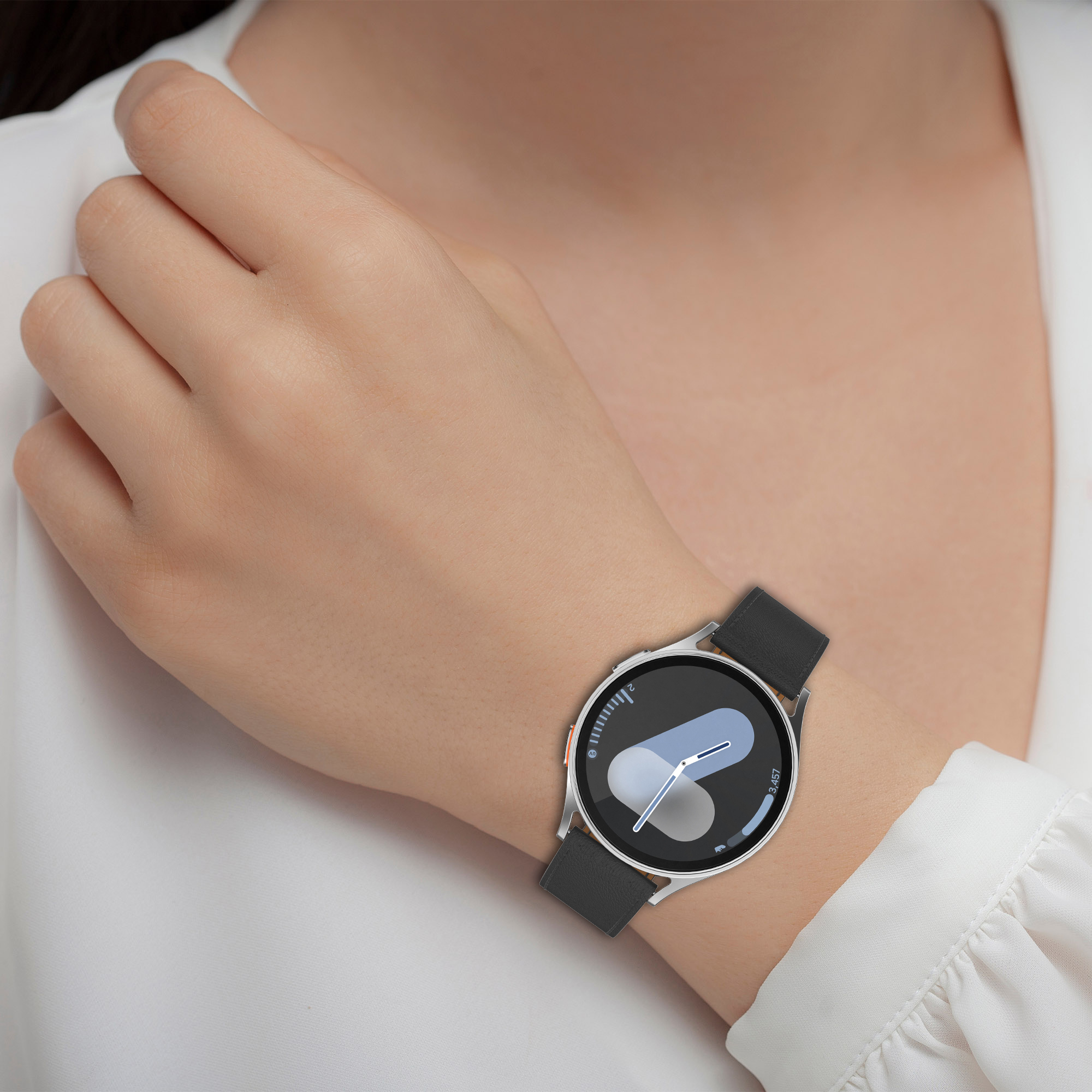 Eine Person trägt eine Smartwatch am Handgelenk, die die Uhrzeit und das Zifferblatt zeigt.