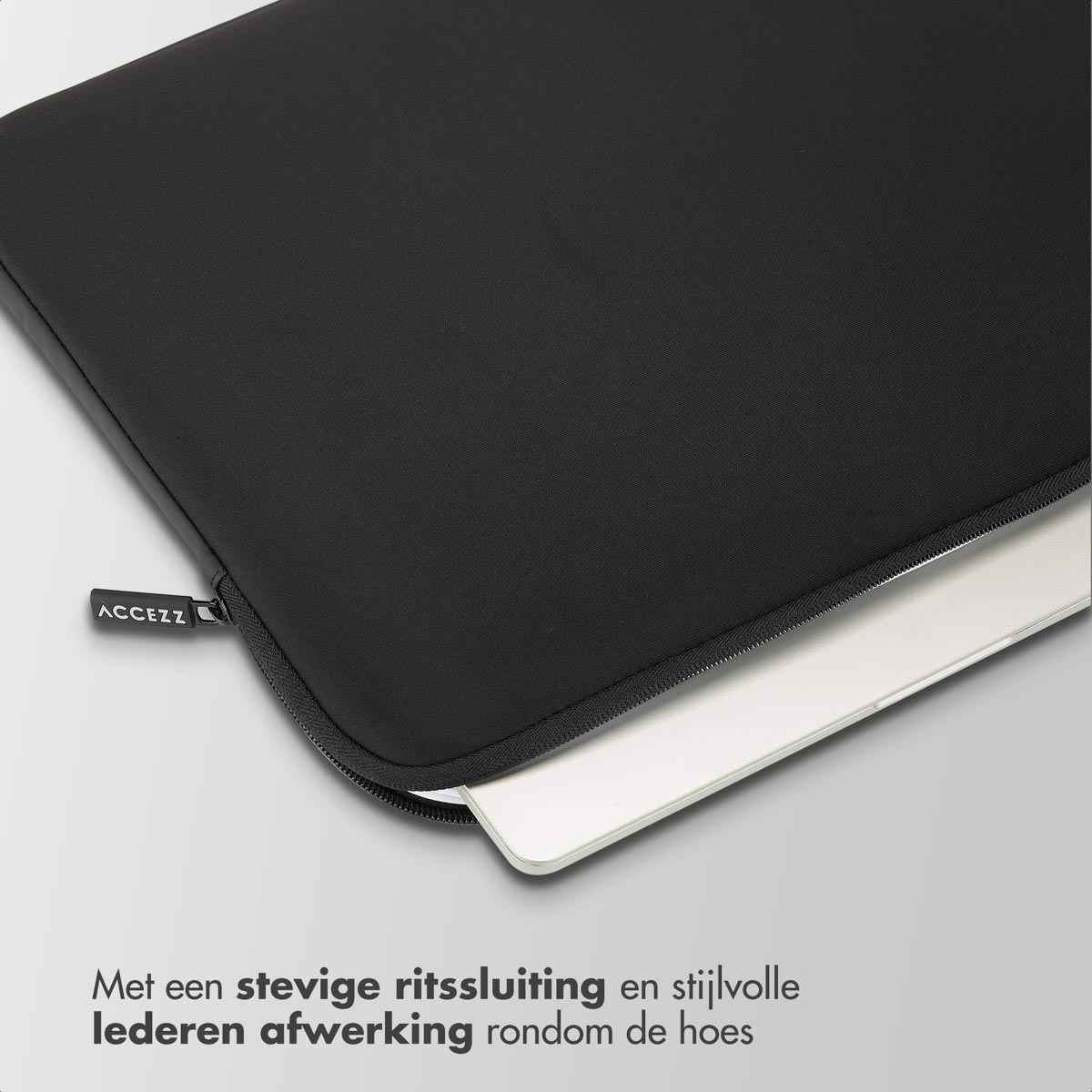 Zwarte laptoptas met een rits. Een witte laptop gedeeltelijk in de tas.