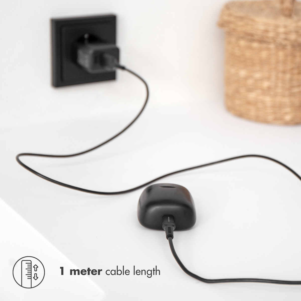 Station de charge noire avec câble noir. Le câble est connecté à une prise murale.