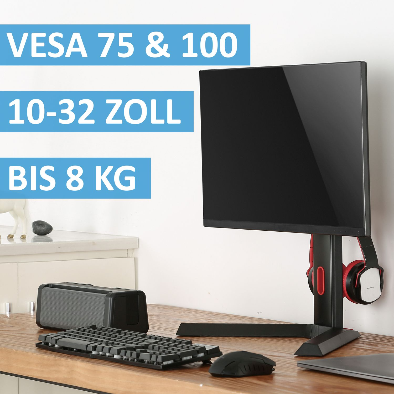 Ein Monitor auf einem schwarzen Ständer. Kopfhörer hängen an der Seite. Tastatur und Maus sind auf dem Tisch.