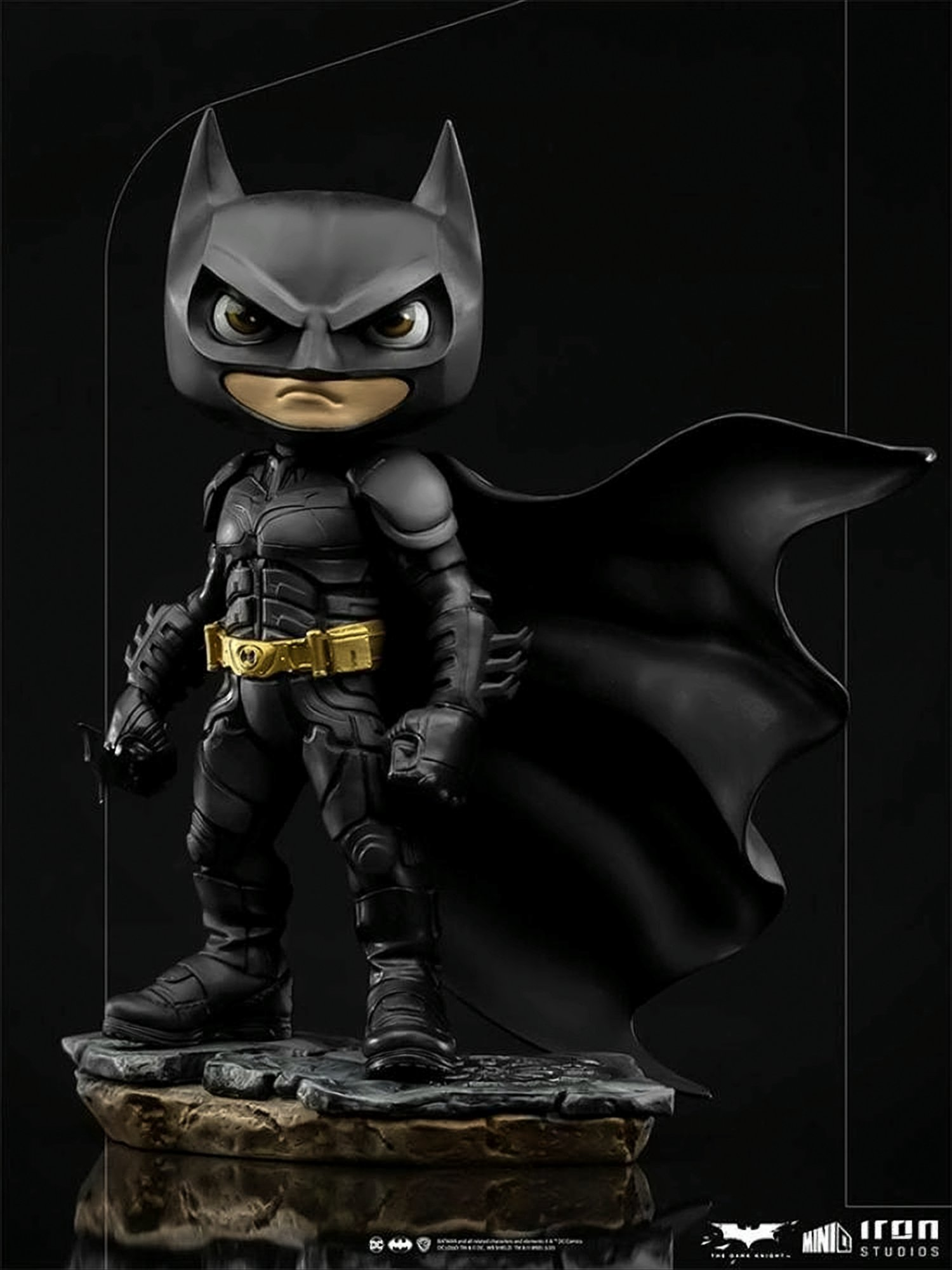 Batman-Figur. Die Dark Knight-Figur steht auf einer Basis. Er trägt einen schwarzen Anzug mit Umhang und goldenem Gürtel.
