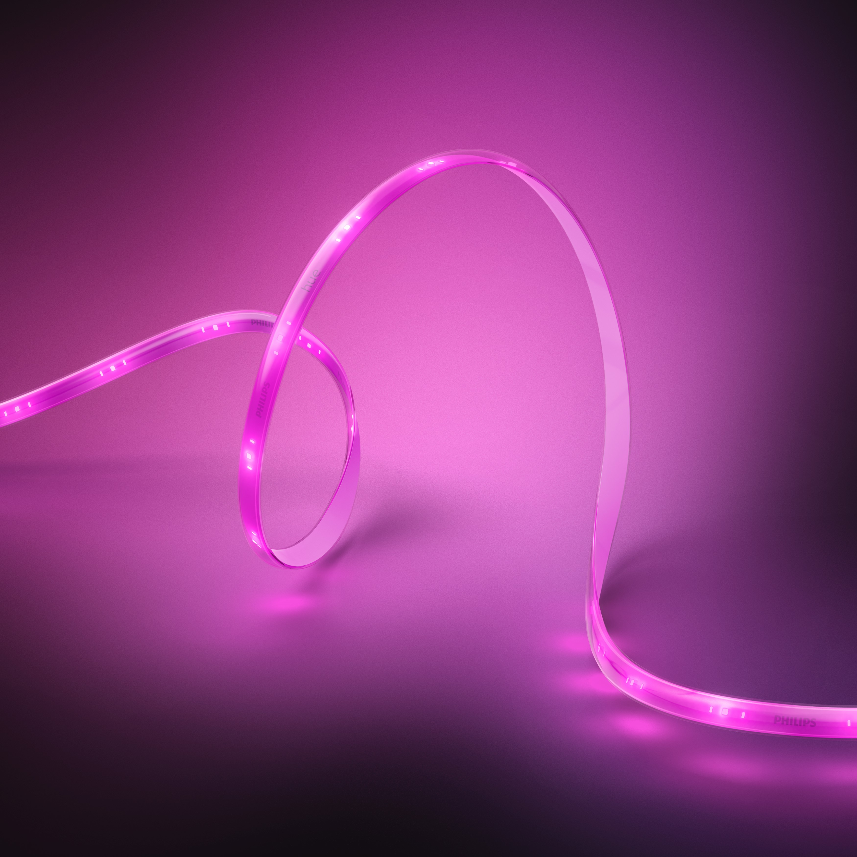 Bande lumineuse LED rose, courbée et allumée, sur un fond rose dégradé.