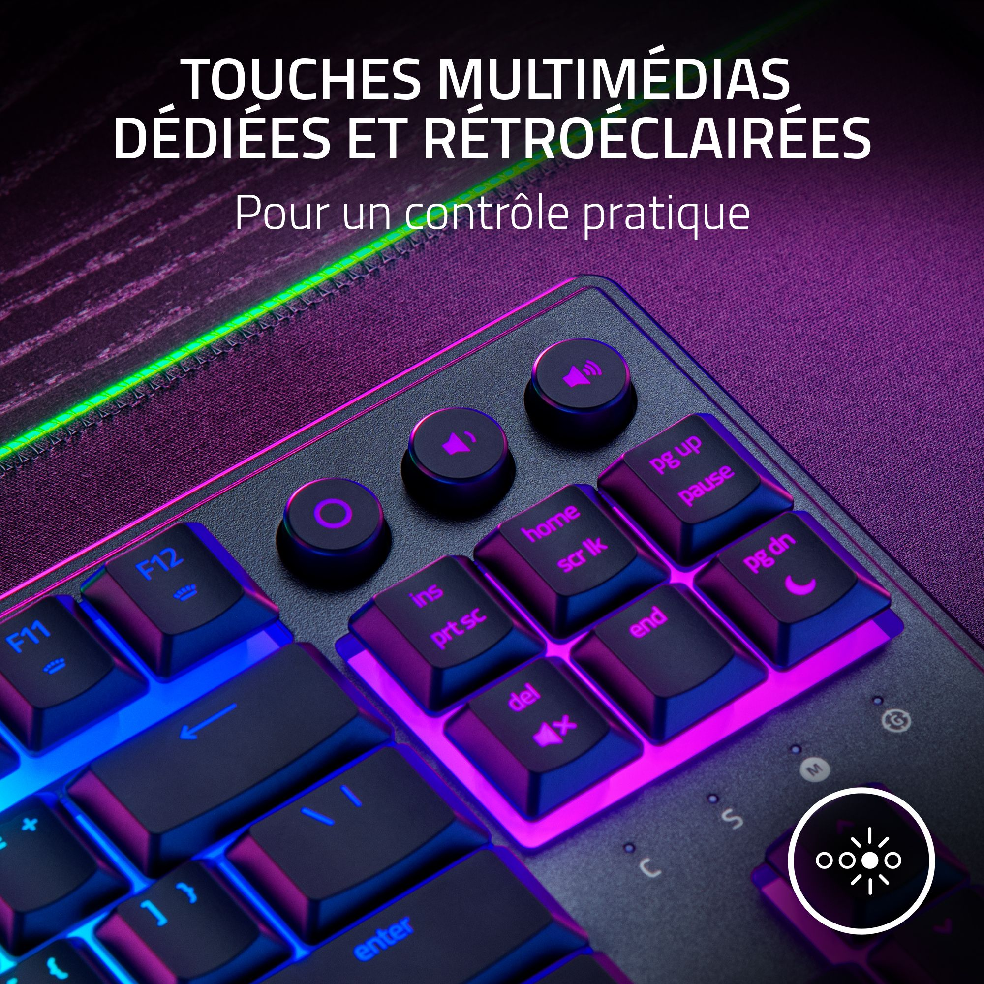 Primo piano di una tastiera retroilluminata con tasti multimediali. Luci viola e blu illuminano tasti e testo.