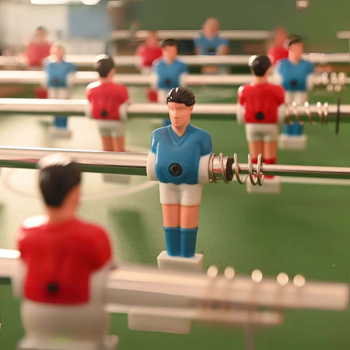 Foosball table with players in red and blue uniforms on green field.