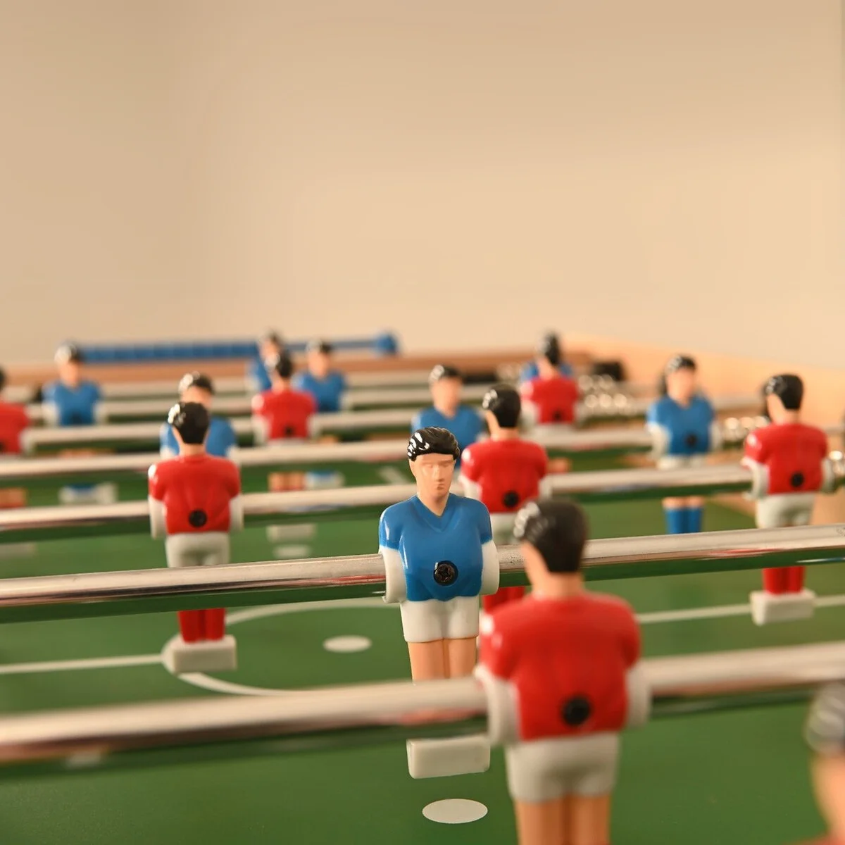 Foosball table game in action. Figures in red and blue. Green field background.