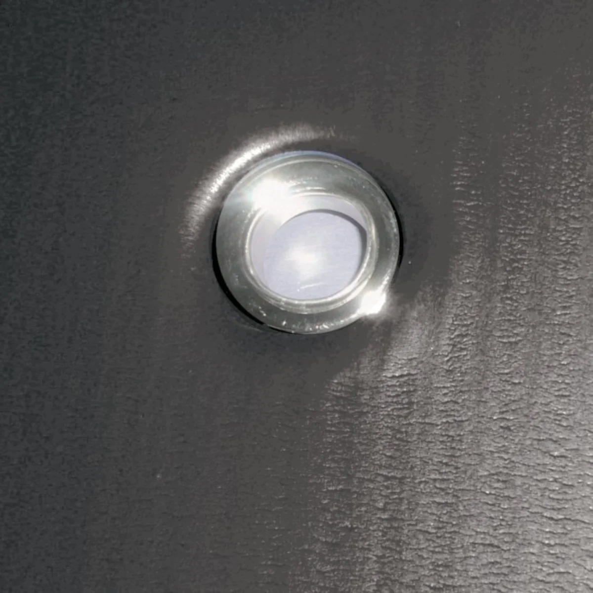 A close-up of a small, silver light fixture on a dark surface.