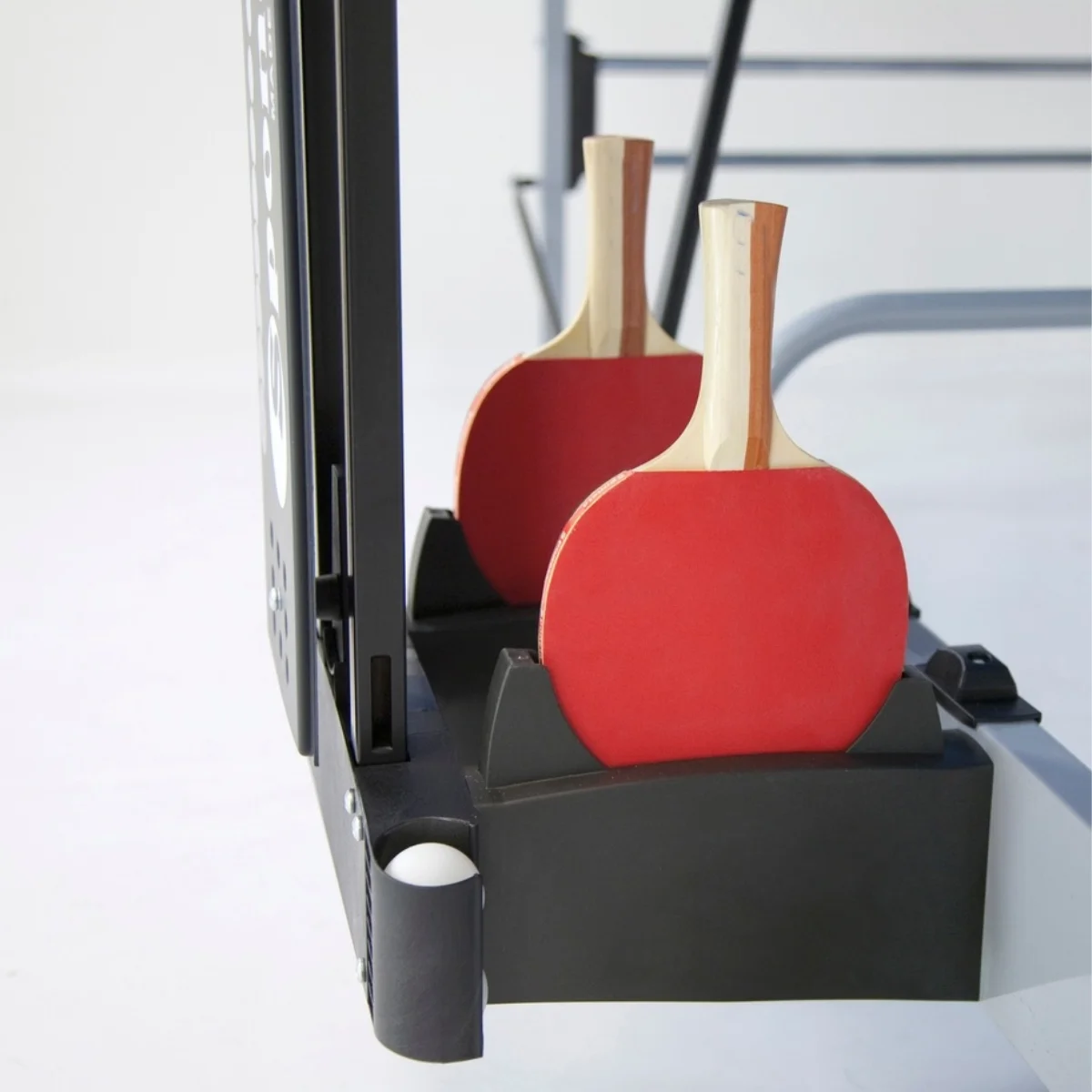 Two red ping pong paddles with wooden handles are in a black holder. White background.