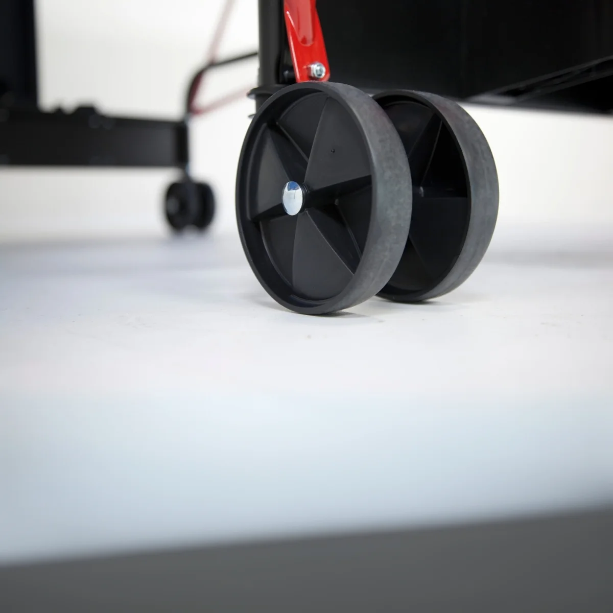 Two black wheels from a ping pong table. White background. Black frame visible in the background.