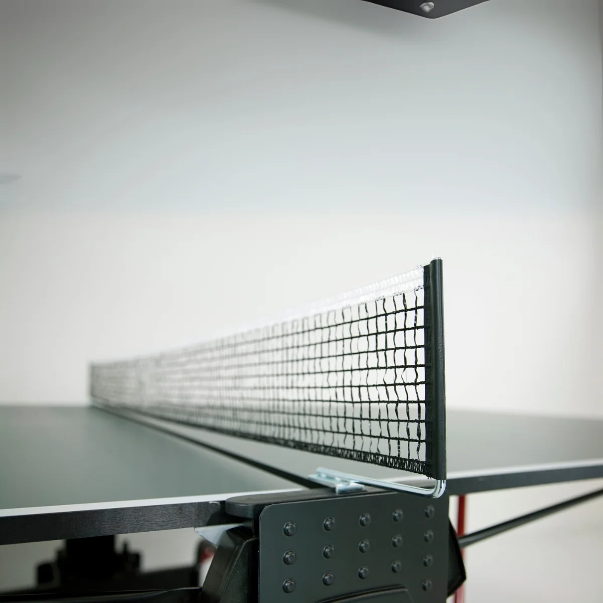A ping pong net, set up, with the net and frame in focus, against a plain white background.