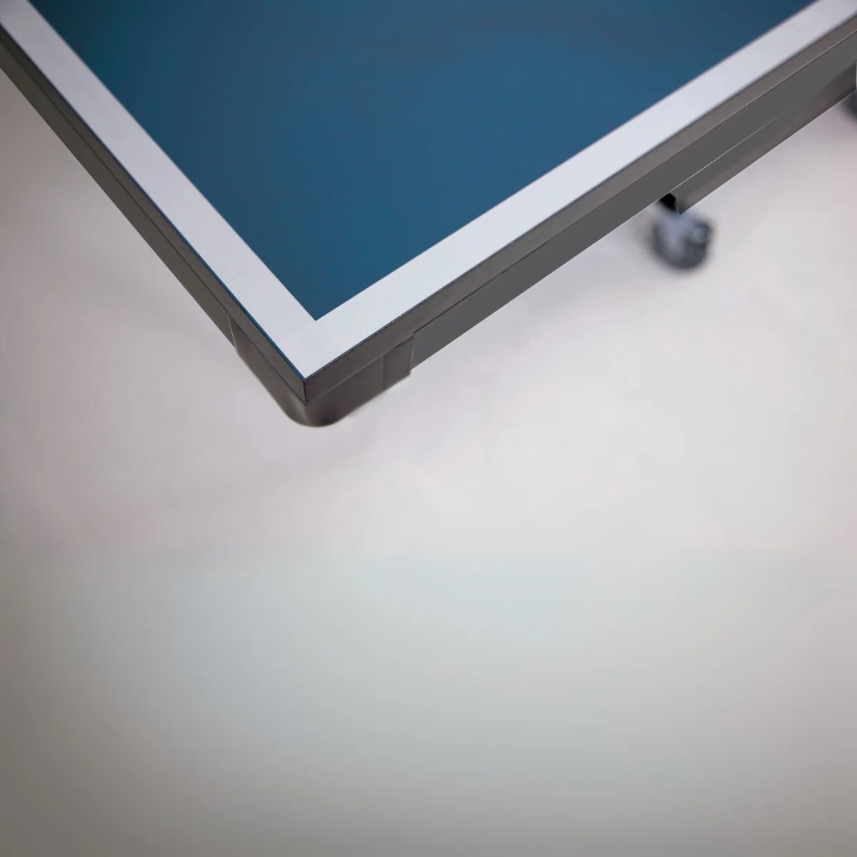 The corner of a blue table with a white trim, the rest is a white backdrop.