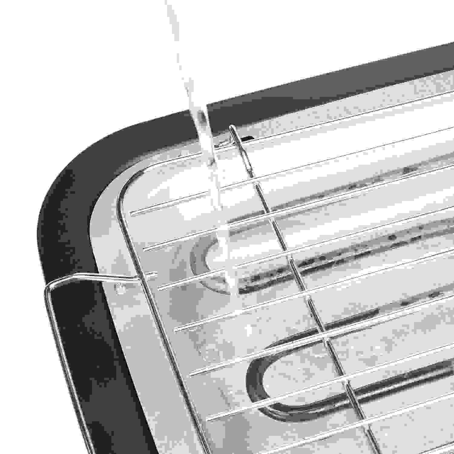 Water pouring onto a metal grill, likely for cleaning or cooking.