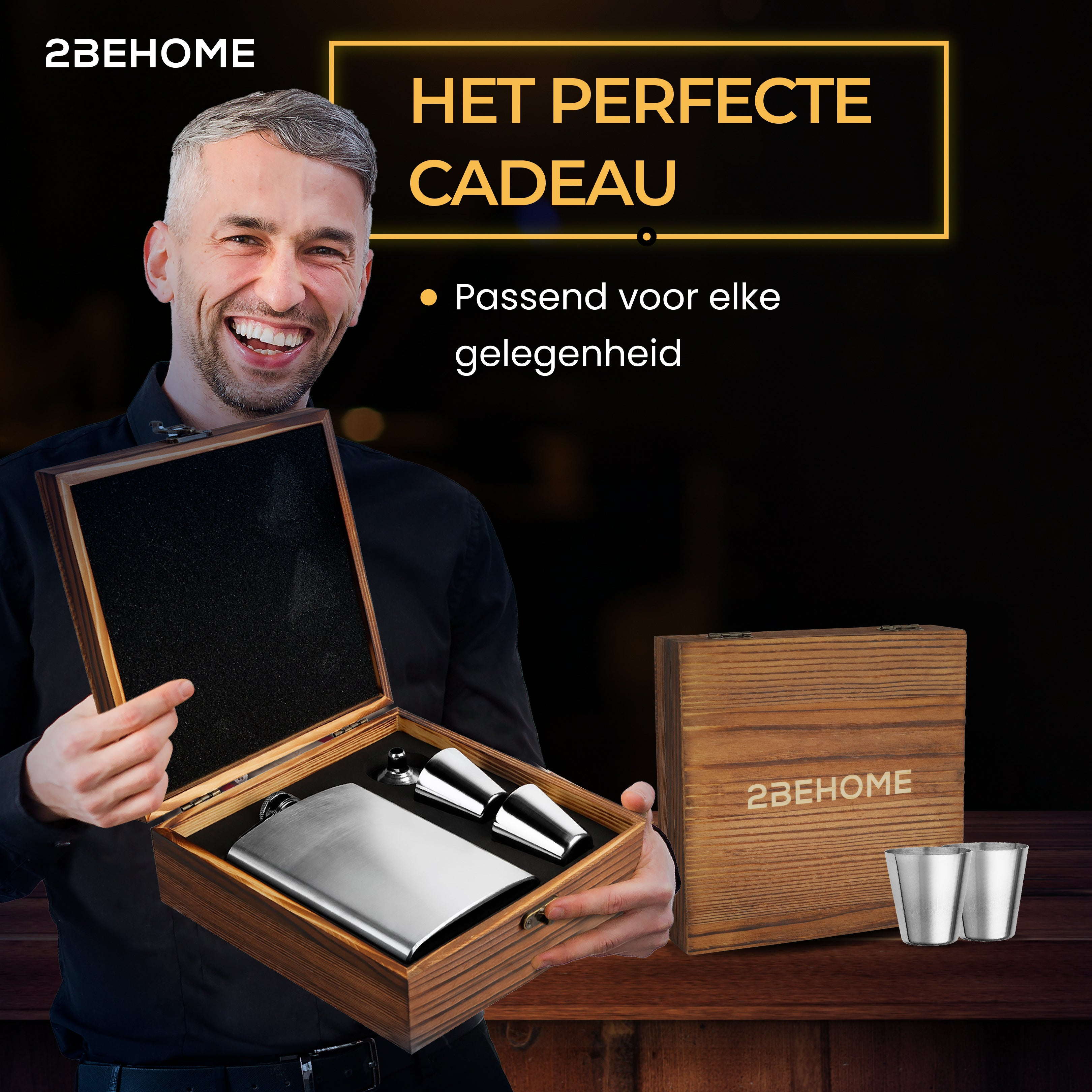A man holding a flask set in a wooden box. Two shot glasses are also in the box.