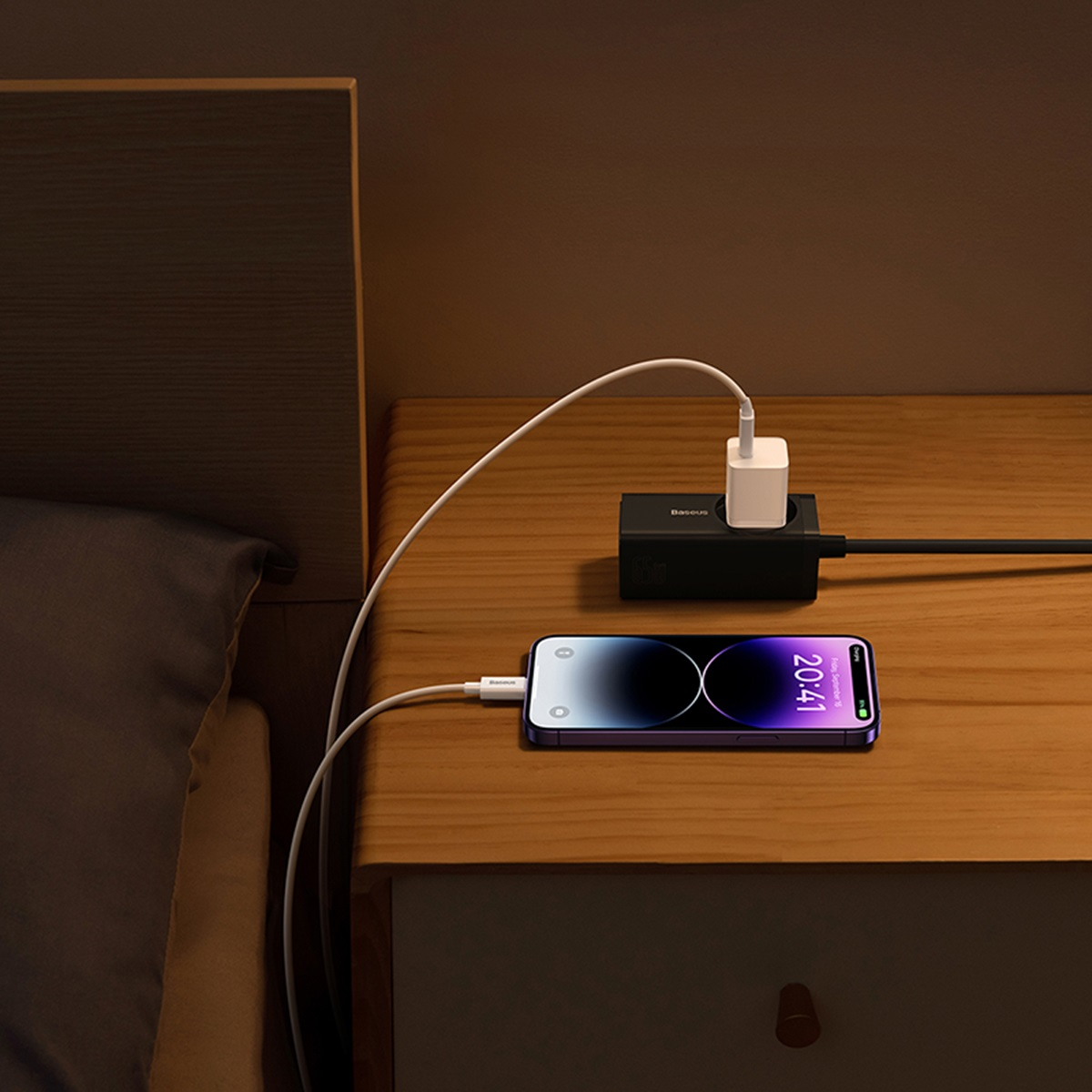 Een telefoon die oplaadt op een nachtkastje. De telefoon toont de tijd 20:41. Een oplader is aangesloten.