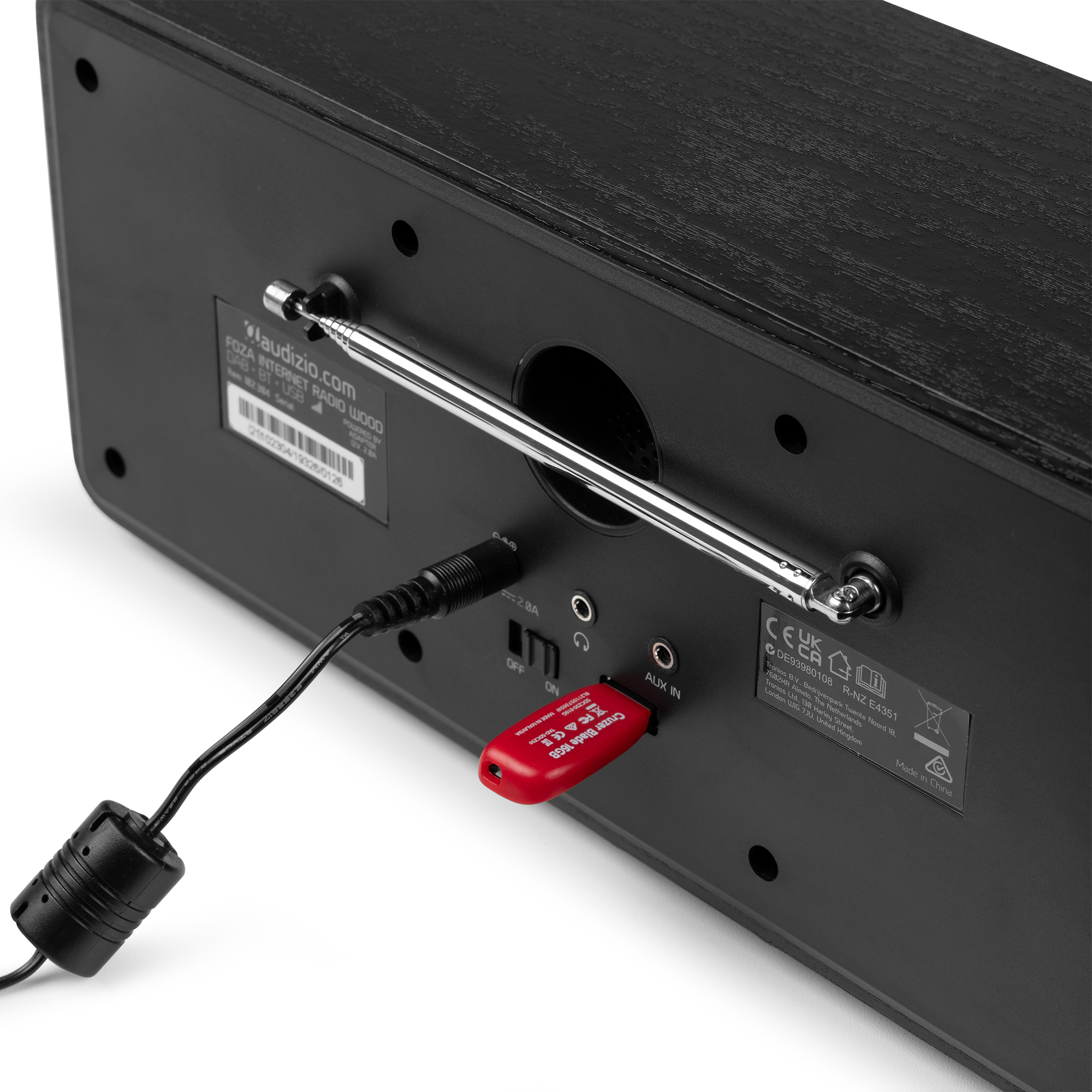 La parte trasera de una radio de madera con antena y puerto USB es visible.