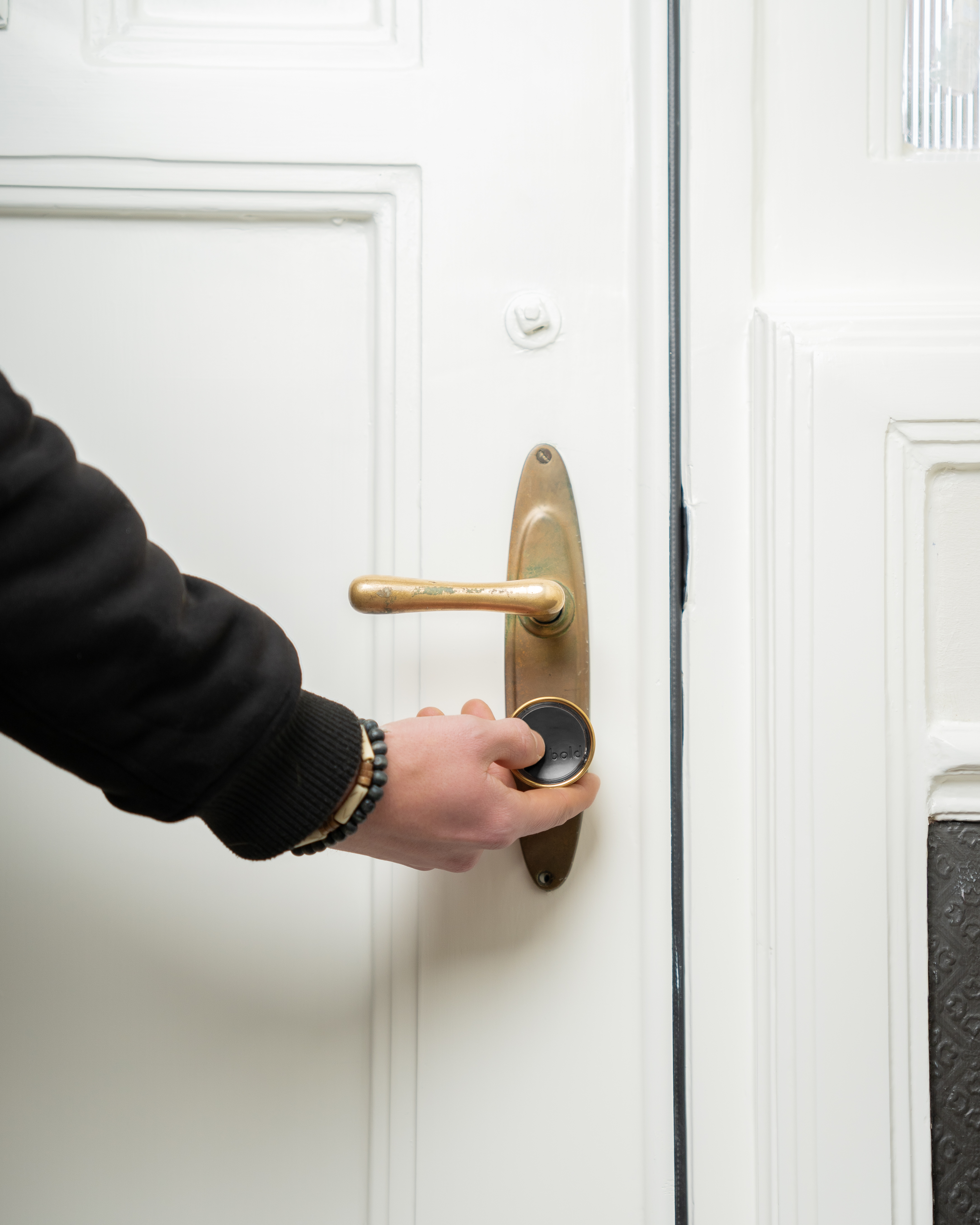 Hand turning a gold door knob on a white door.