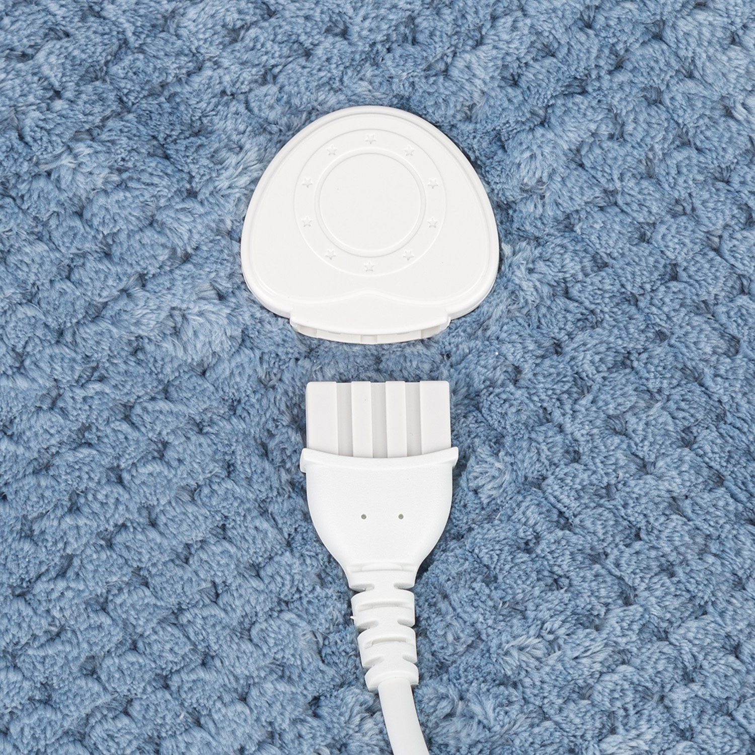 Un adattatore di alimentazione bianco con un connettore bianco e una superficie blu a motivi sullo sfondo.