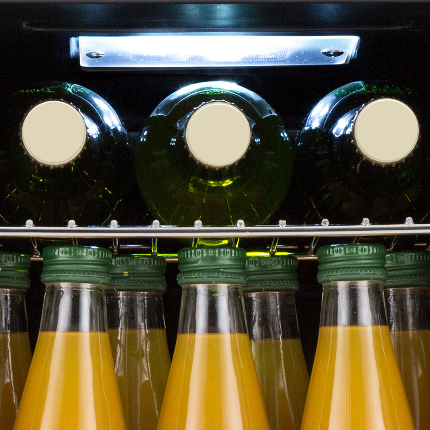 Bottiglie di vetro di succo in un frigorifero. Bottiglie verdi con liquido giallo.