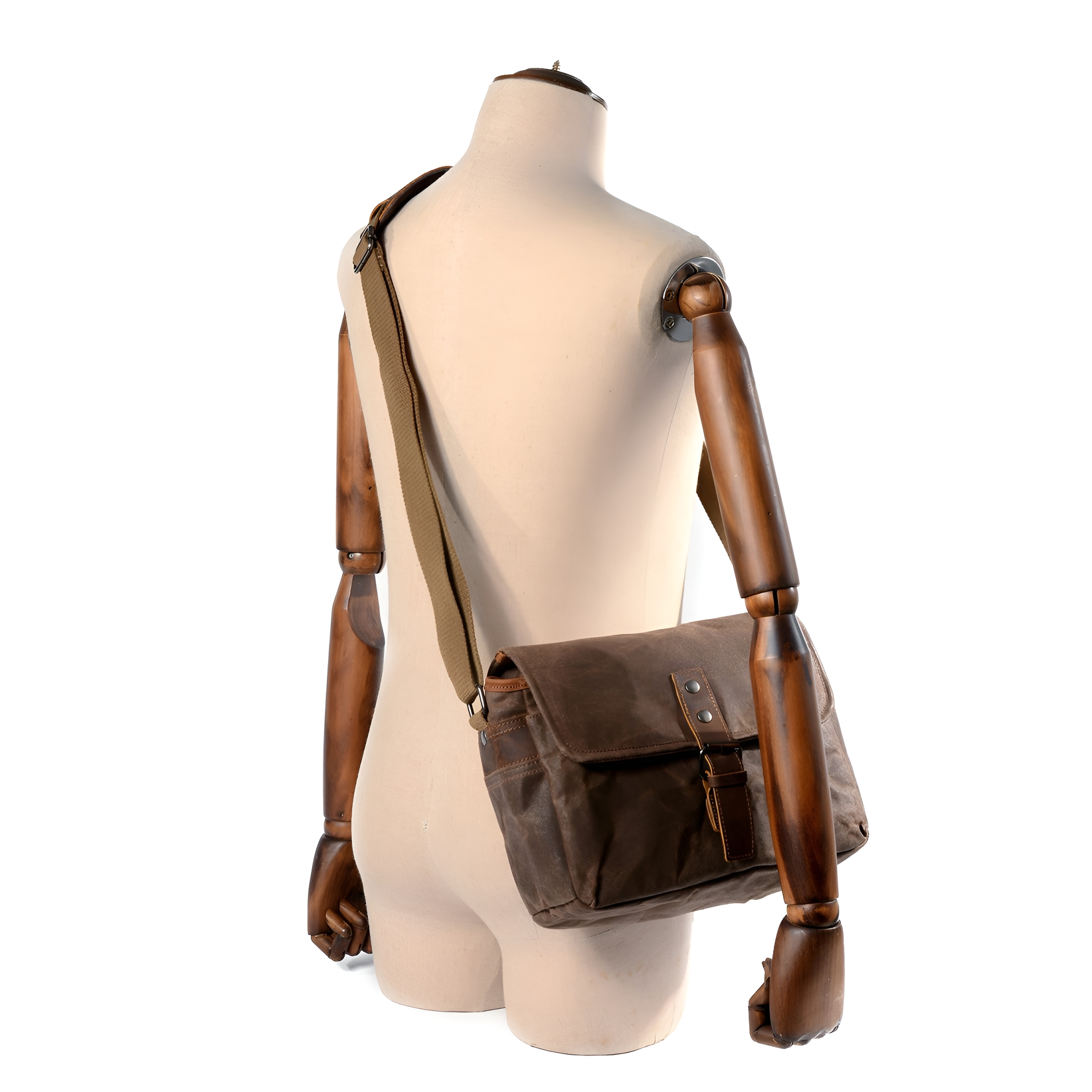 Eine Schaufensterpuppe mit brauner Tasche. Die Tasche hat eine Klappe und einen Riemen. Der Hintergrund ist weiß.