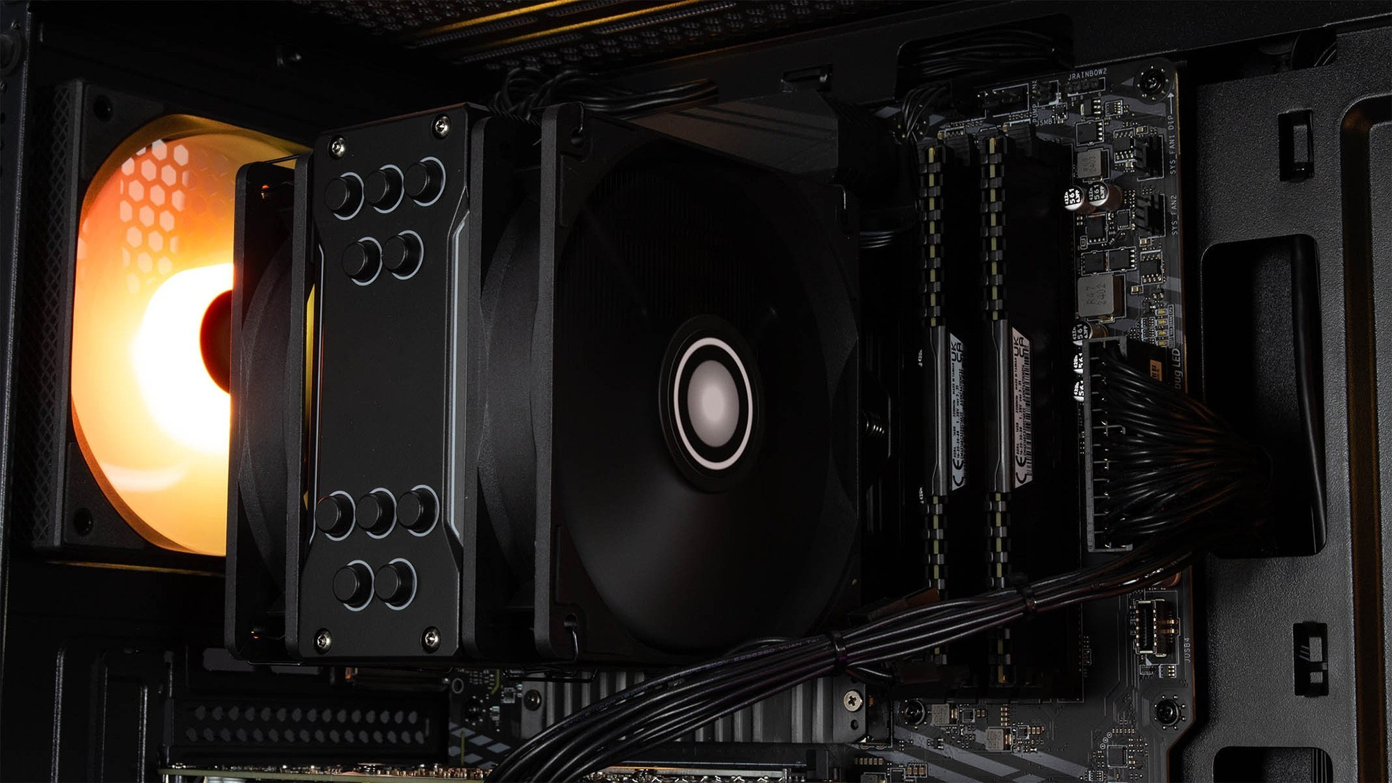 All'interno di un case per PC nero, un dissipatore CPU nero con ventola e una scheda madre con componenti.
