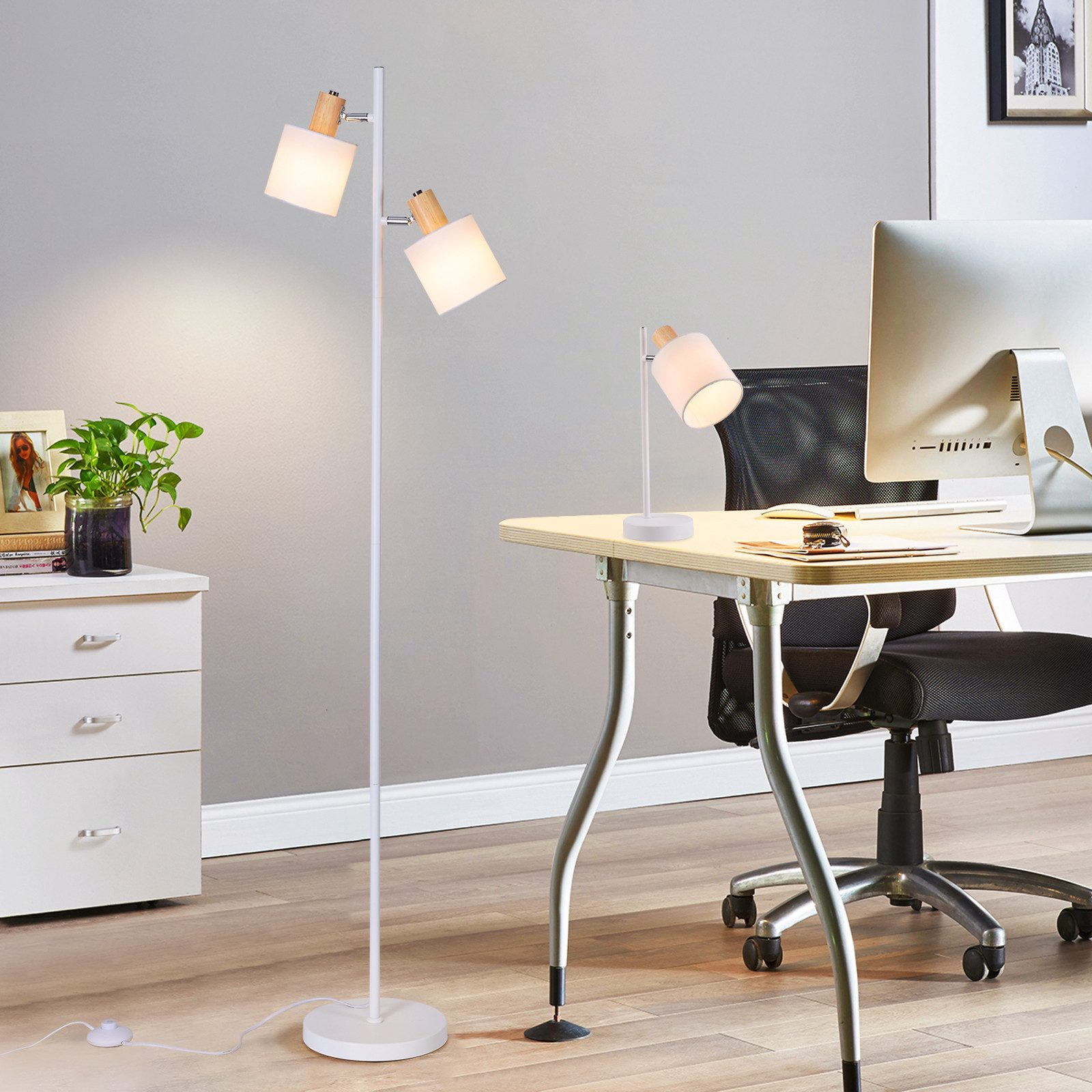 Büro mit zwei weißen Lampen. Eine ist eine Stehlampe, die andere steht auf einem Schreibtisch.