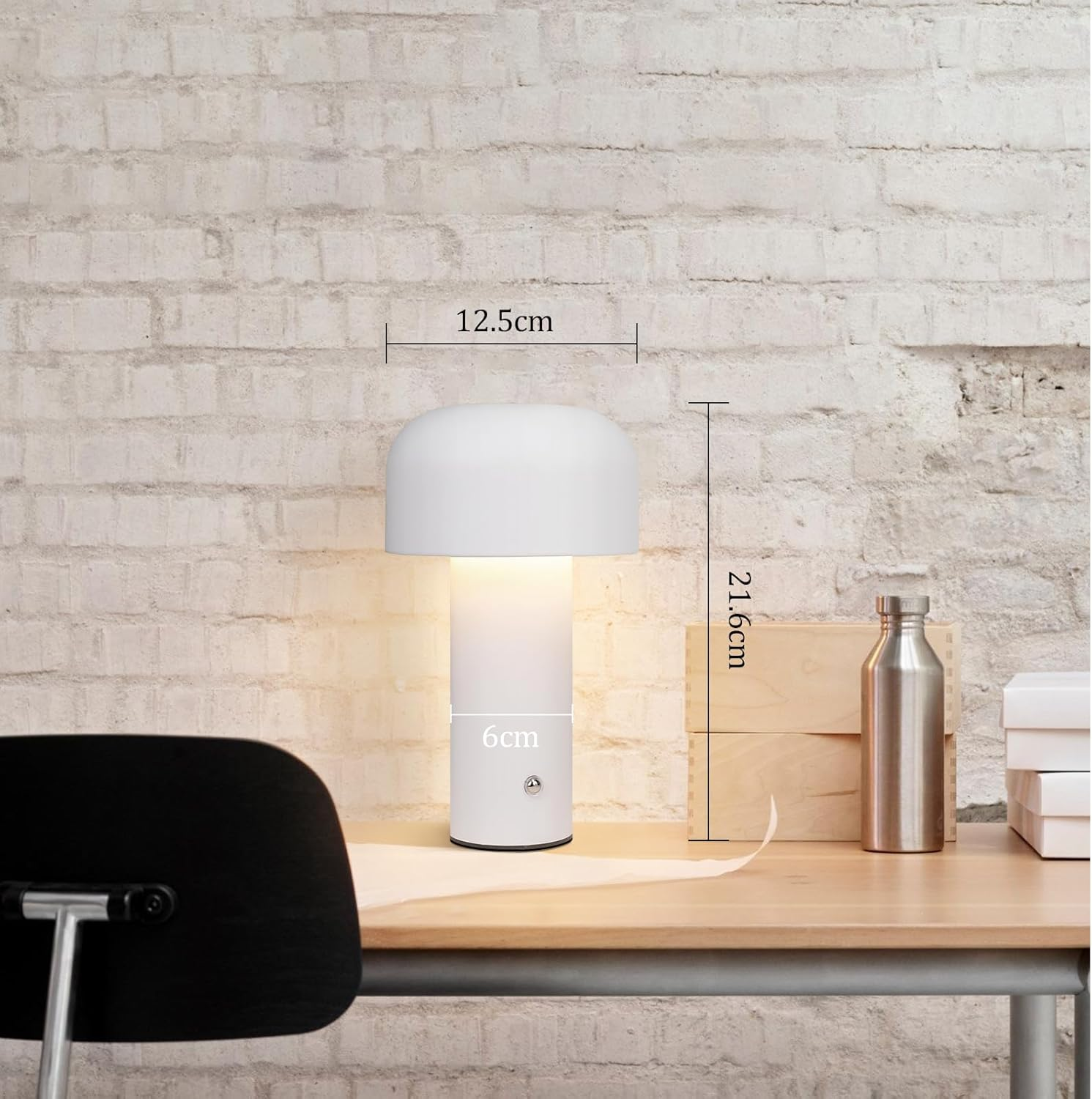 Biała lampa z zaokrągloną górą i cylindryczną podstawą, na drewnianym biurku, z wymiarami i czarnym krzesłem.