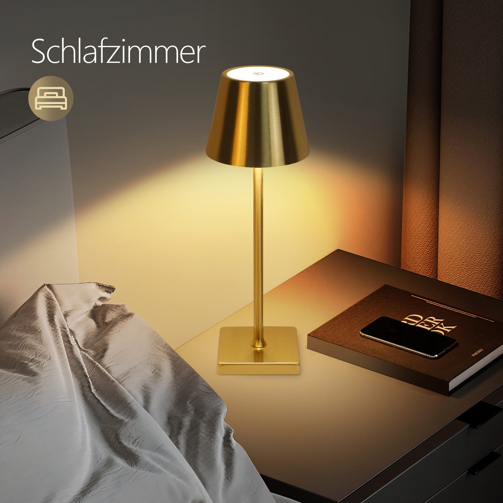 Złota lampa na szafce nocnej w sypialni. Obok leżą telefon i książka.