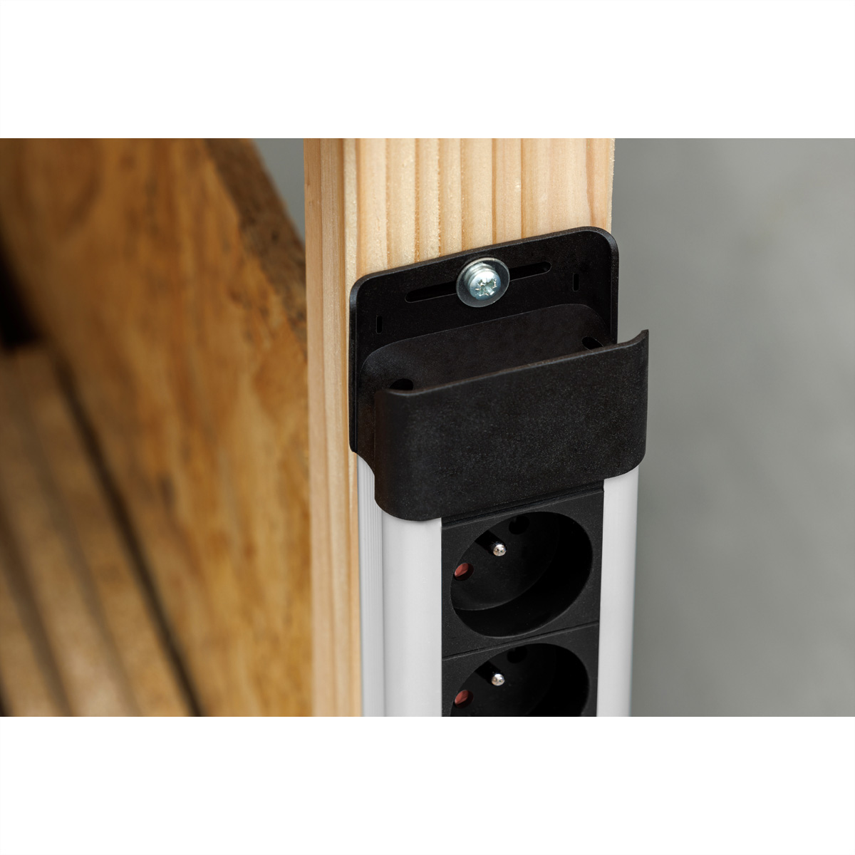 Een stekkerdoos met twee stopcontacten gemonteerd op een houten constructie, schroef en beugel zichtbaar.