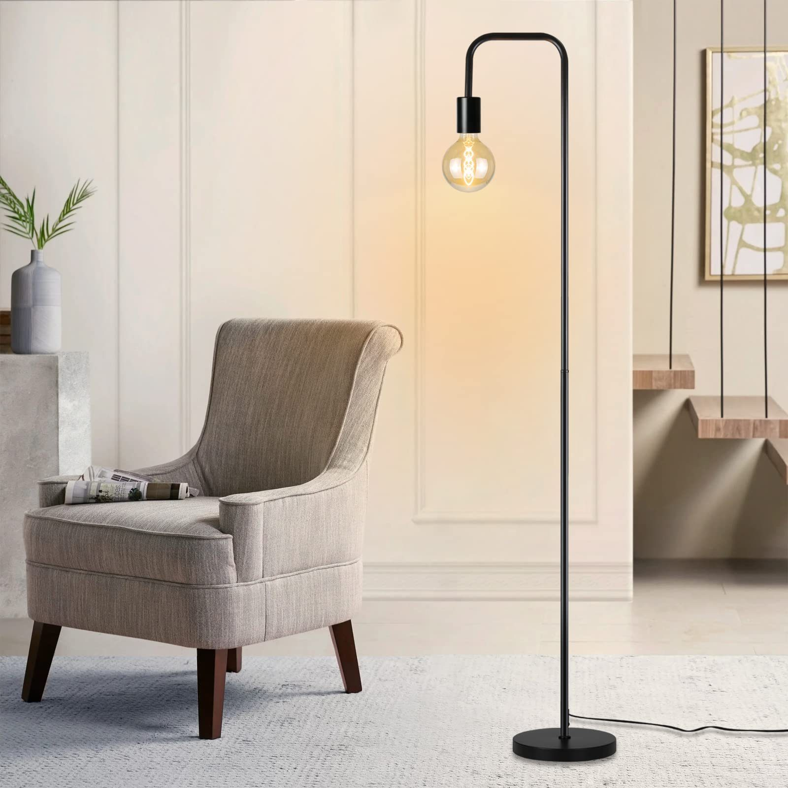 Schwarze Stehlampe mit runder Glühbirne, neben einem Sessel. Raum mit cremefarbenen Wänden und einem Gemälde.