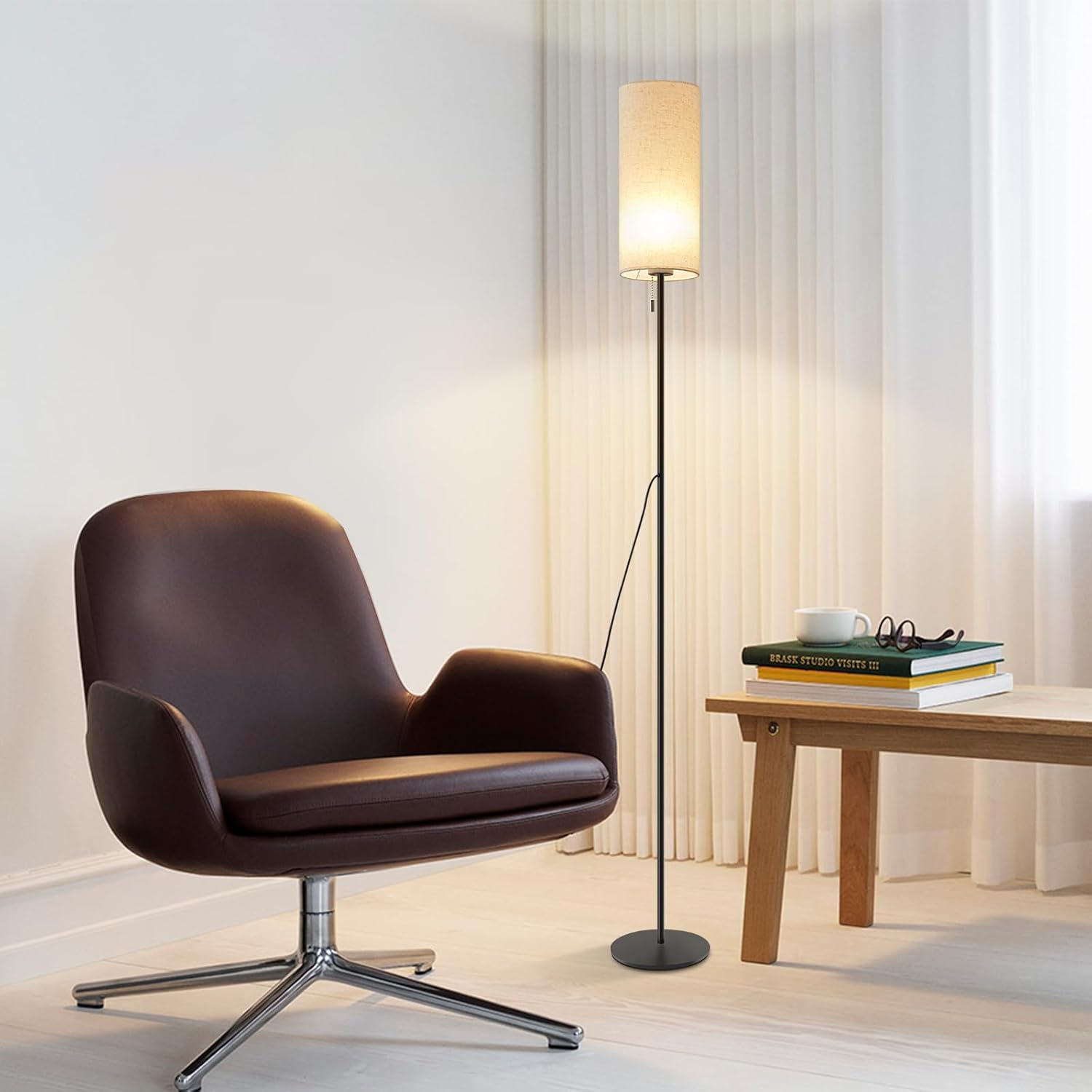 Pokój z brązowym krzesłem, lampą i małym stolikiem z książkami i filiżanką.