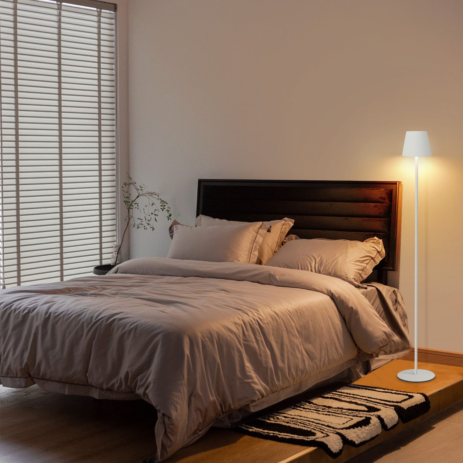 Camera da letto con lampada da terra. Letto e tappeto sono visibili. La stanza ha un design semplice.