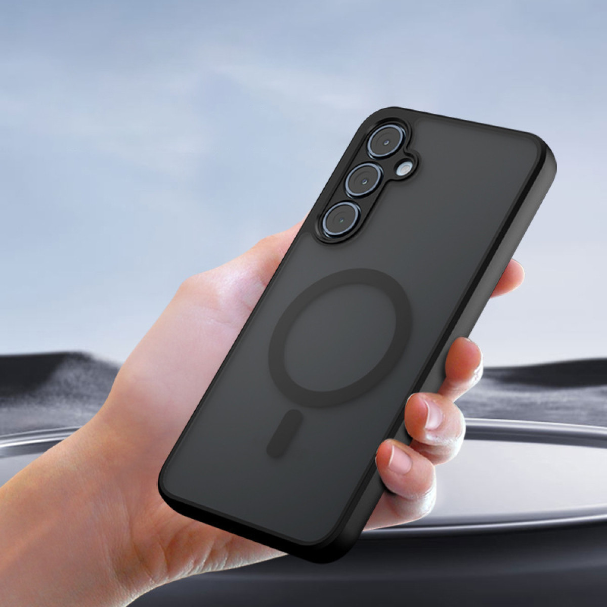 Una custodia per telefono nera con tre ritagli per fotocamera e un magnete circolare sul retro.