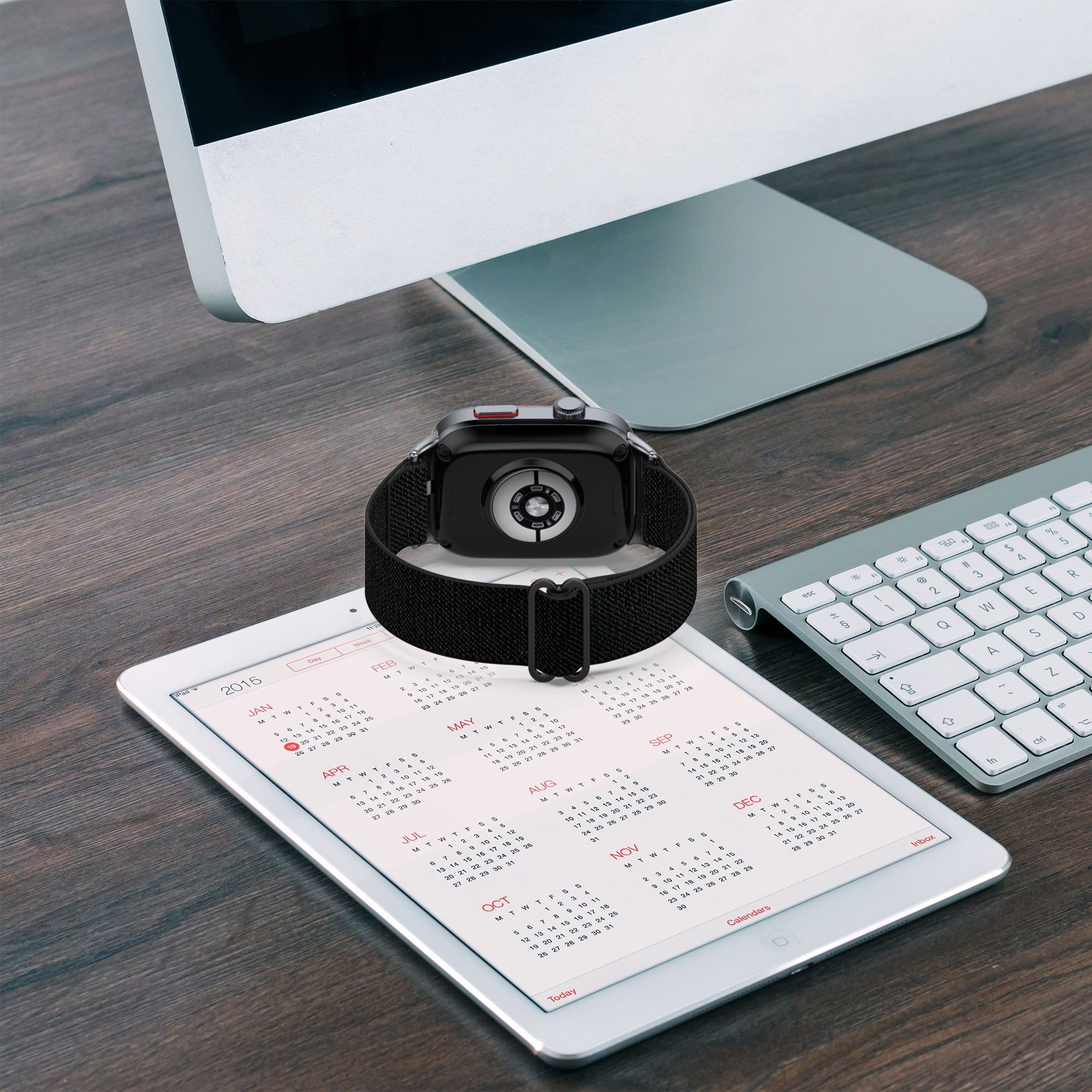 Uno smartwatch con cinturino nero su un tablet con calendario, con computer e tastiera.