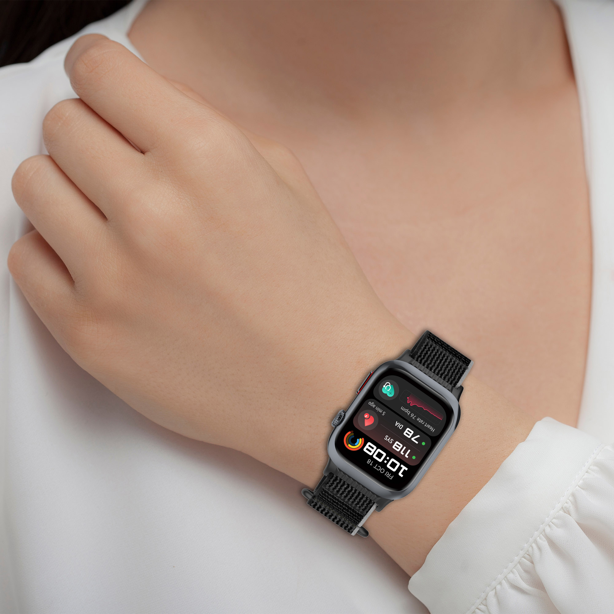 Eine Hand mit einer schwarzen Smartwatch mit Gesundheitsdaten. Weißes Hemd im Hintergrund.