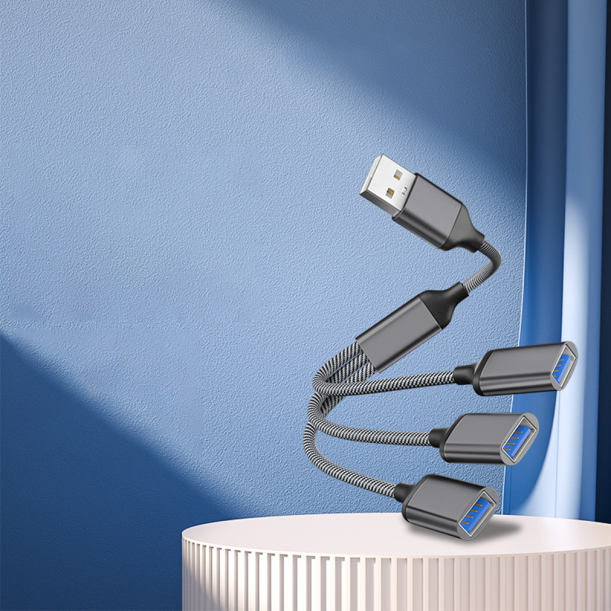 USB-Hub mit 3 Anschlüssen und einem grauen Kabel auf blau-weißem Hintergrund.